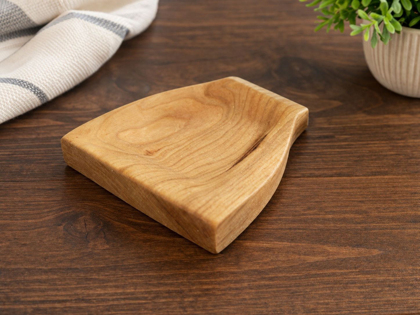 Wooden serving tray on a dark wood table, with a blue and white cloth and potted green plant nearby.