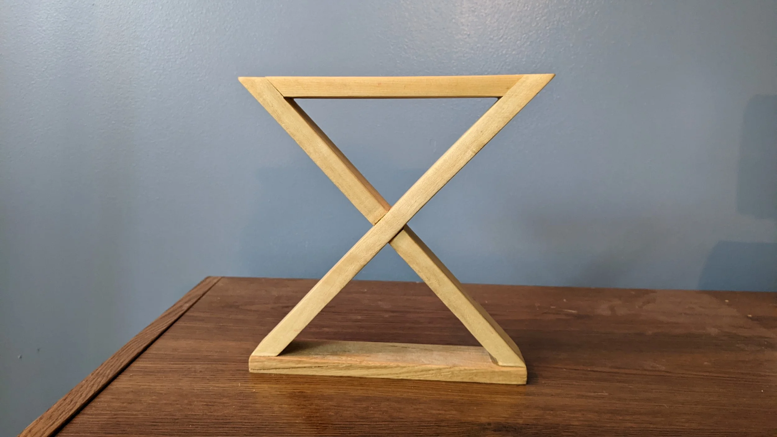 Wooden table with a small wooden folding easel against a blue wall.