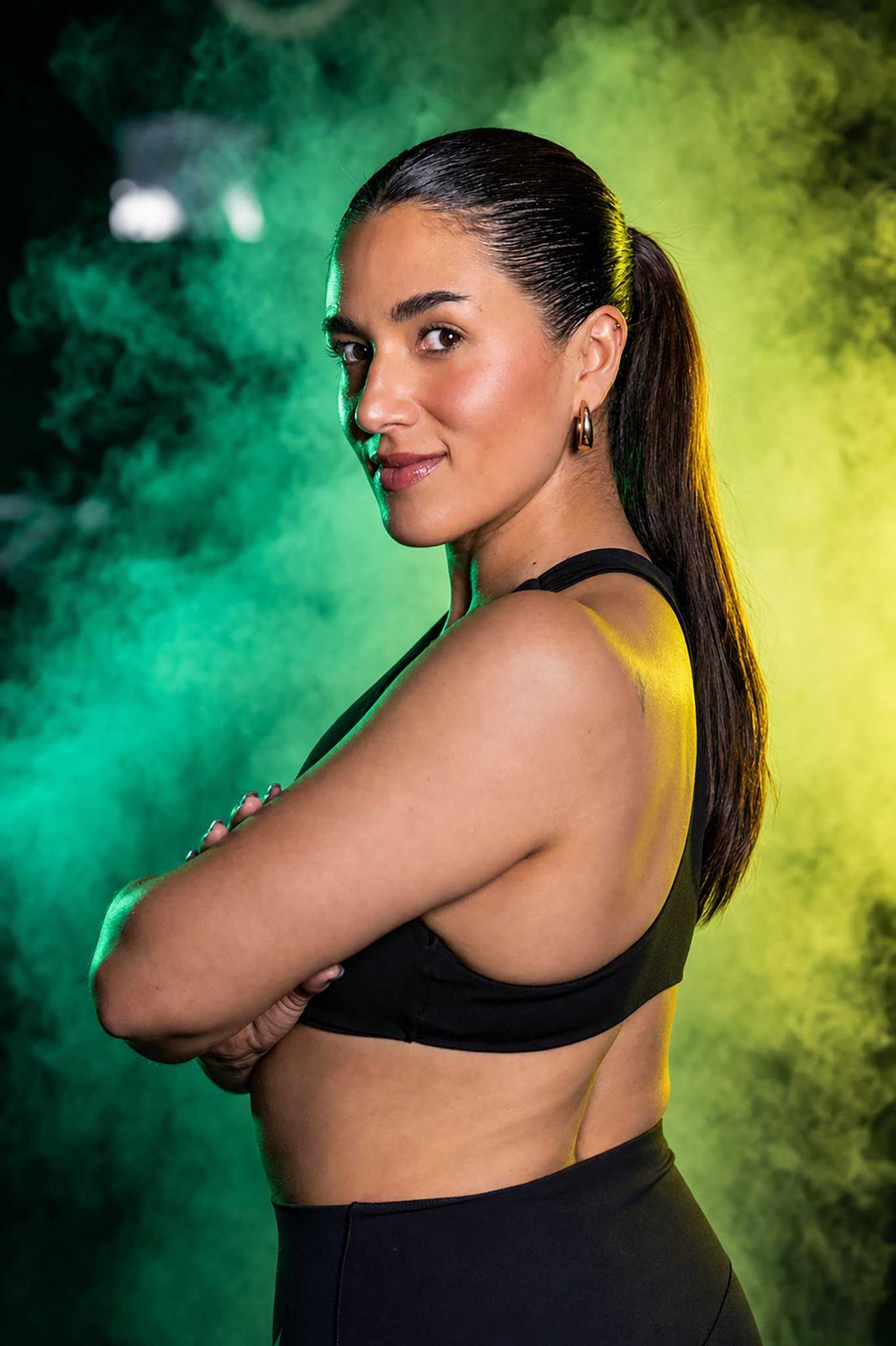 Mujer con ropa deportiva negra en sesión fitness con fondo de humo, fotografía deportiva por Carlos Vega en Puebla.