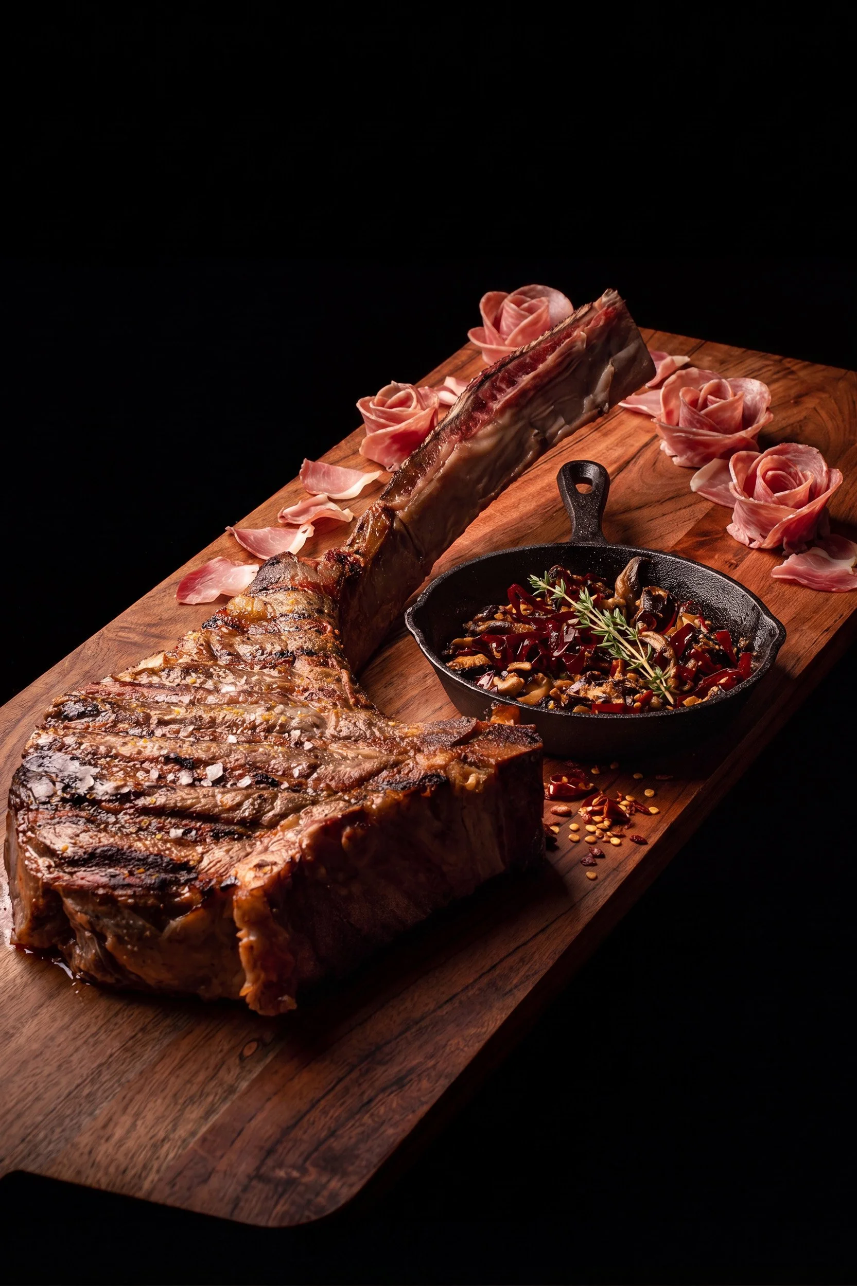 Fotografía gastronómica de corte de carne Tomahawk a la parrilla sobre tabla de madera por Carlos Vega.