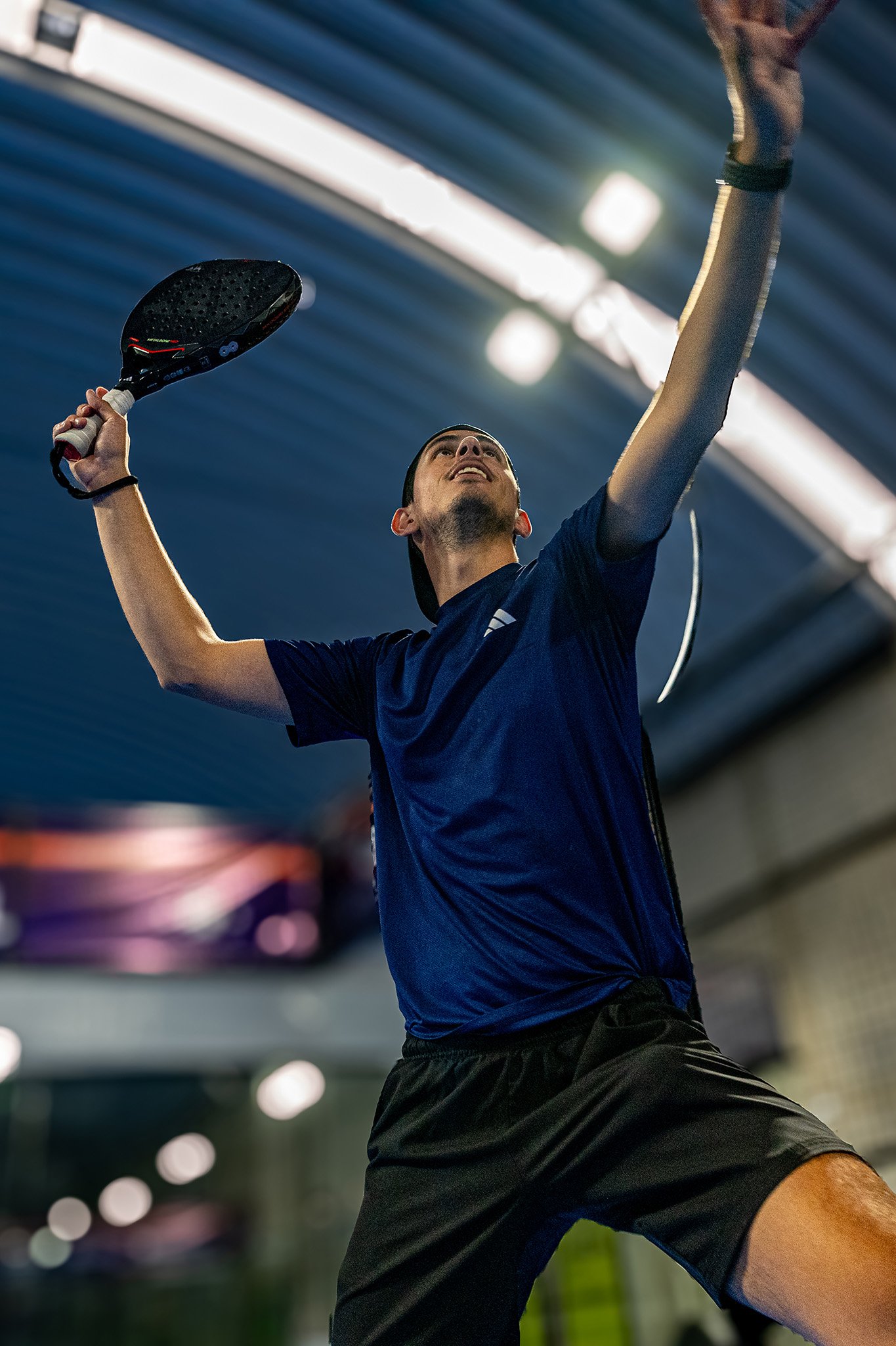 Jugador de pádel en cancha cubierta listo para golpear la pelota, fotografía deportiva por Carlos Vega en Puebla.