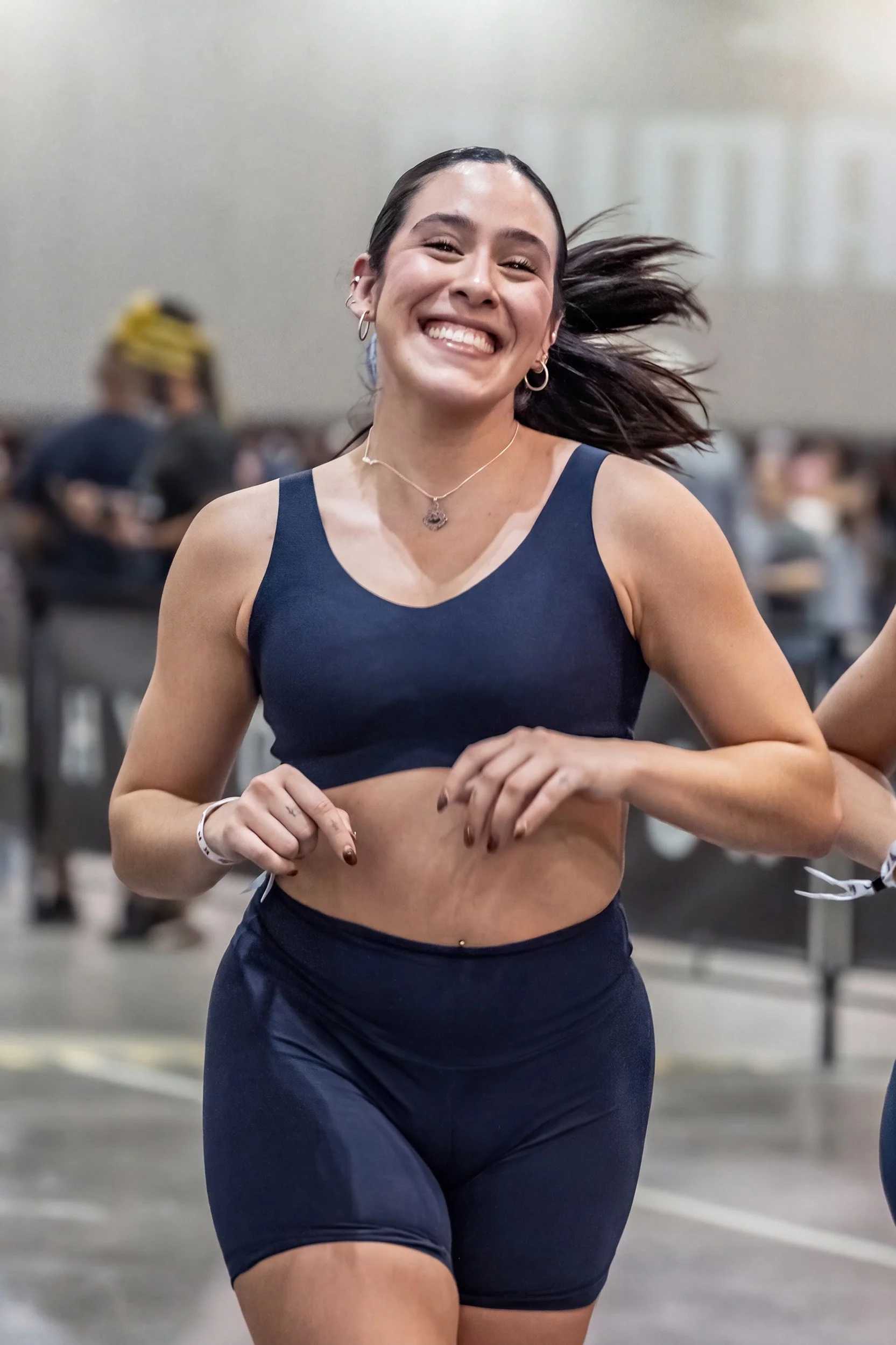 Mujer sonriendo mientras corre en evento atlético, fotografía deportiva por Carlos Vega en Hyrox Puebla.