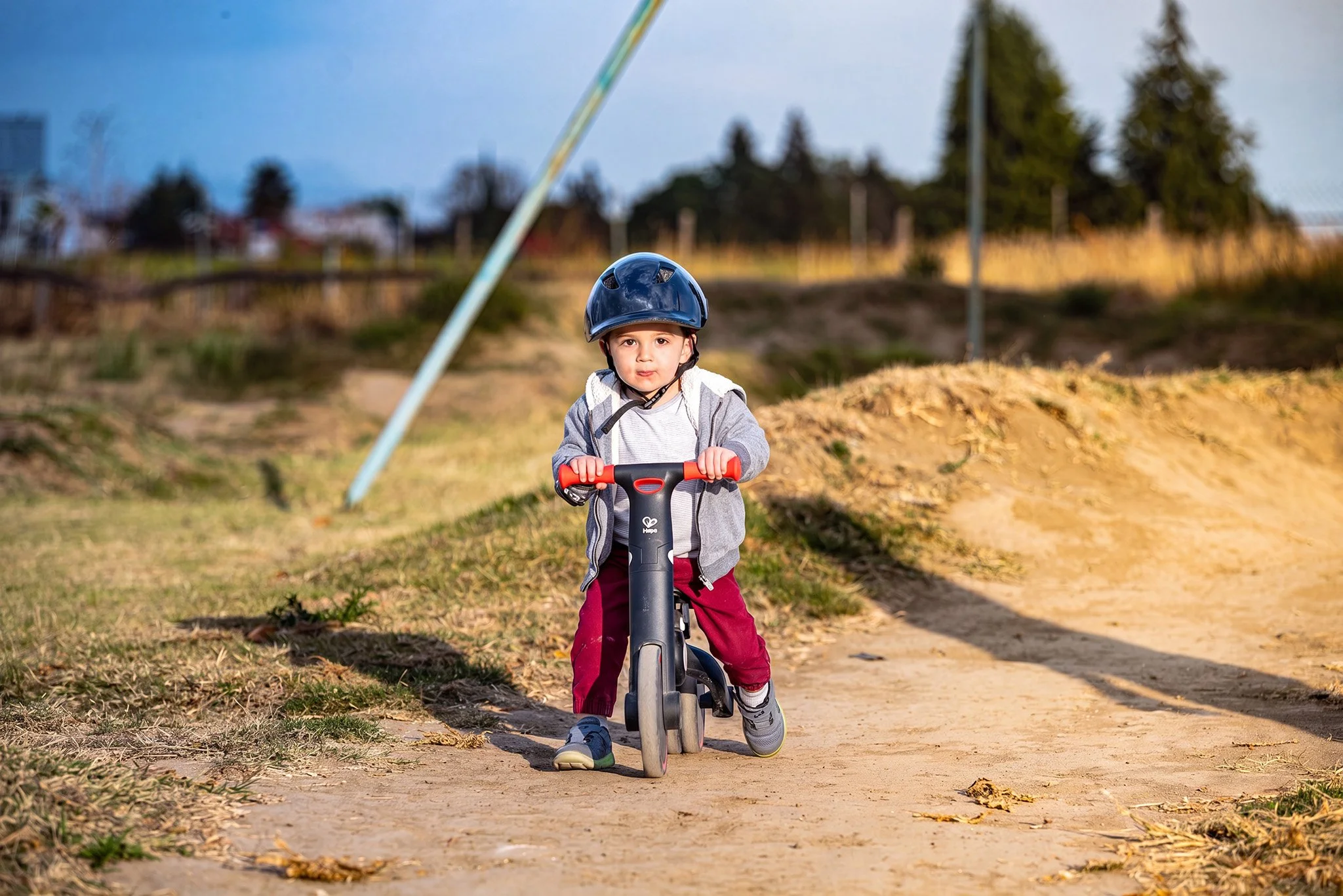 Niño montando bicicleta en camino de tierra al atardecer, fotografía deportiva infantil por Carlos Vega.