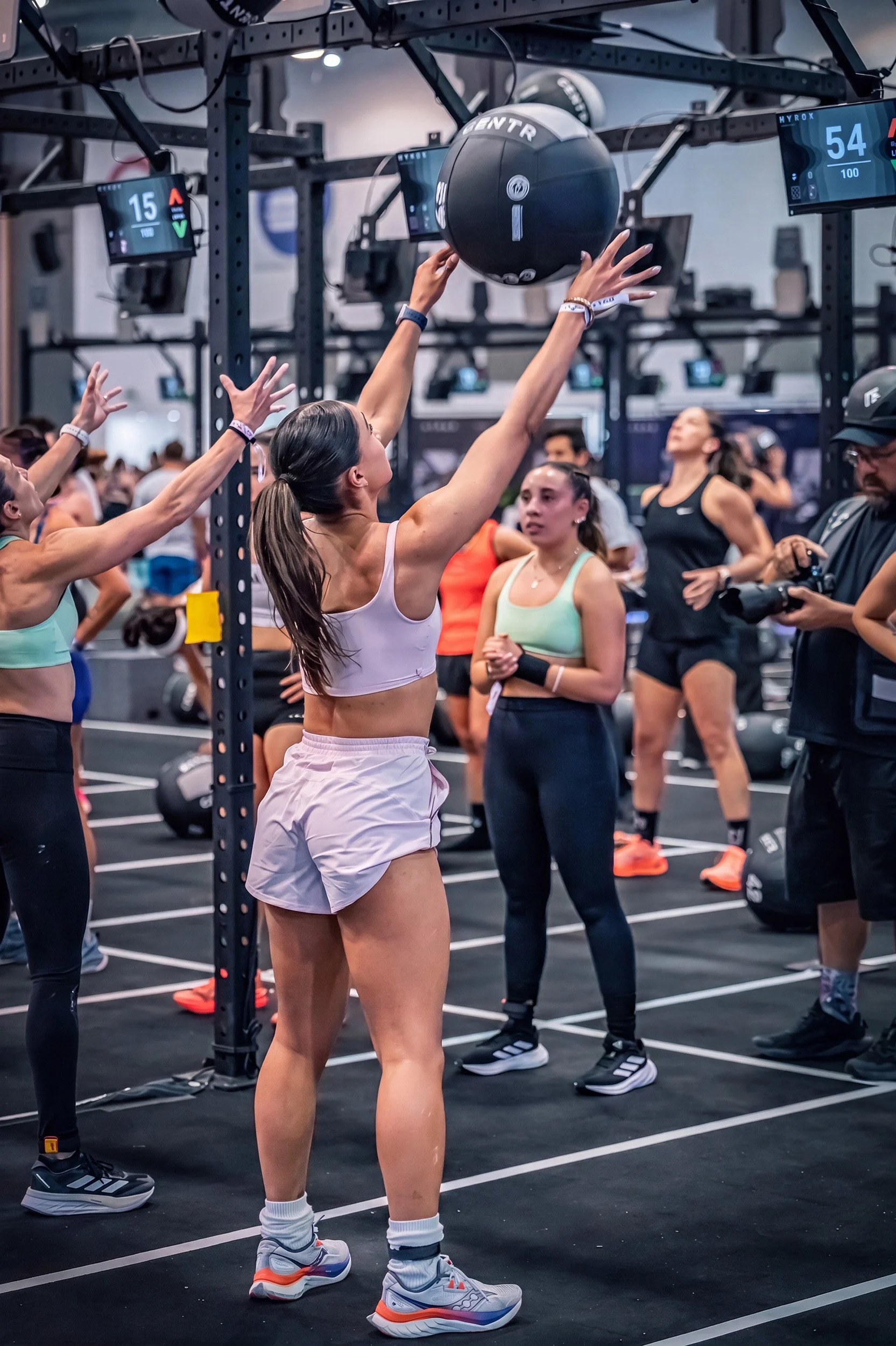 Mujer levantando pelota medicinal durante entrenamiento funcional en gimnasio, fotografía deportiva por Carlos Vega en Hyrox Puebla.