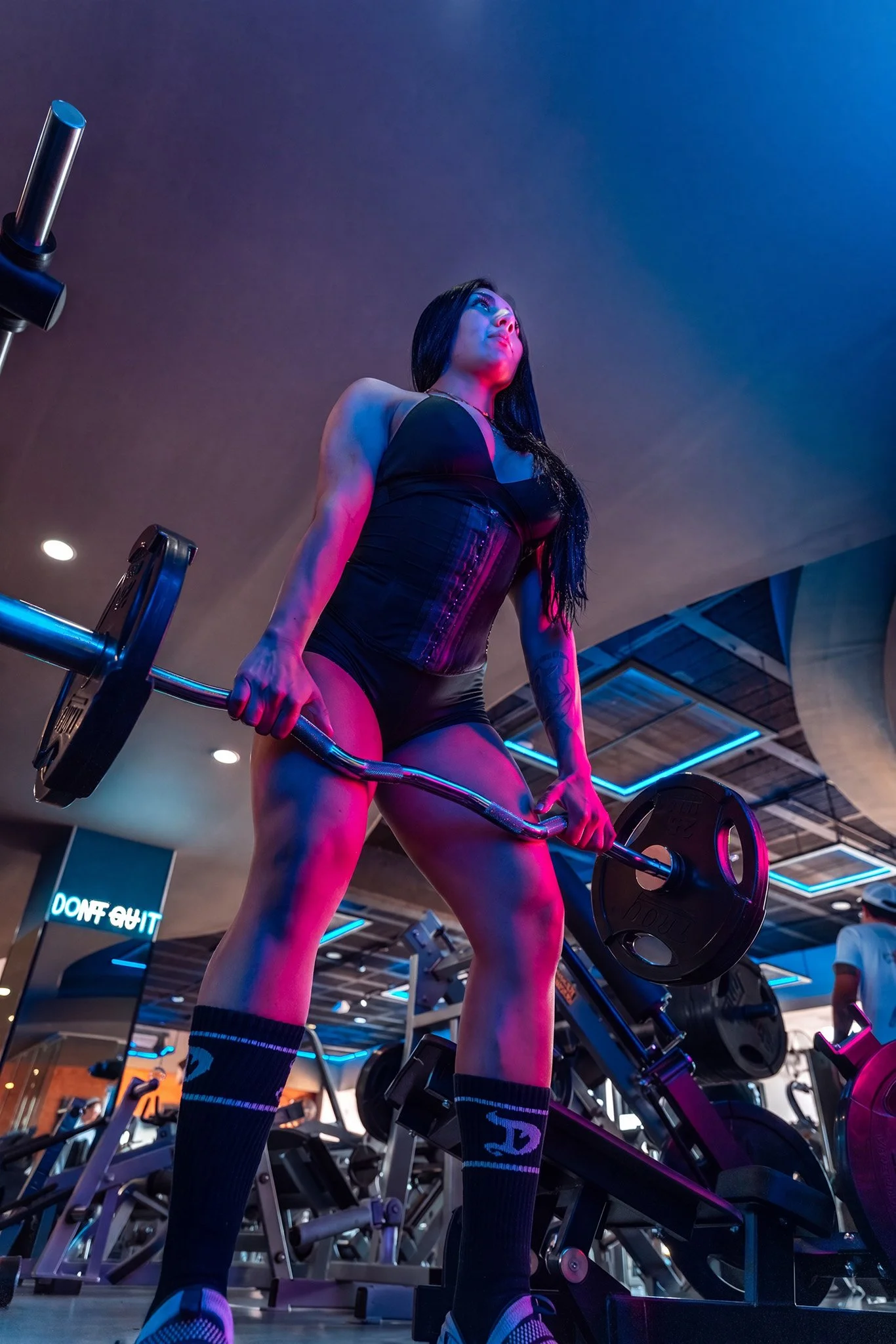 Mujer levantando pesas en gimnasio con iluminación de neón, fotografía fitness profesional por Carlos Vega en Puebla.