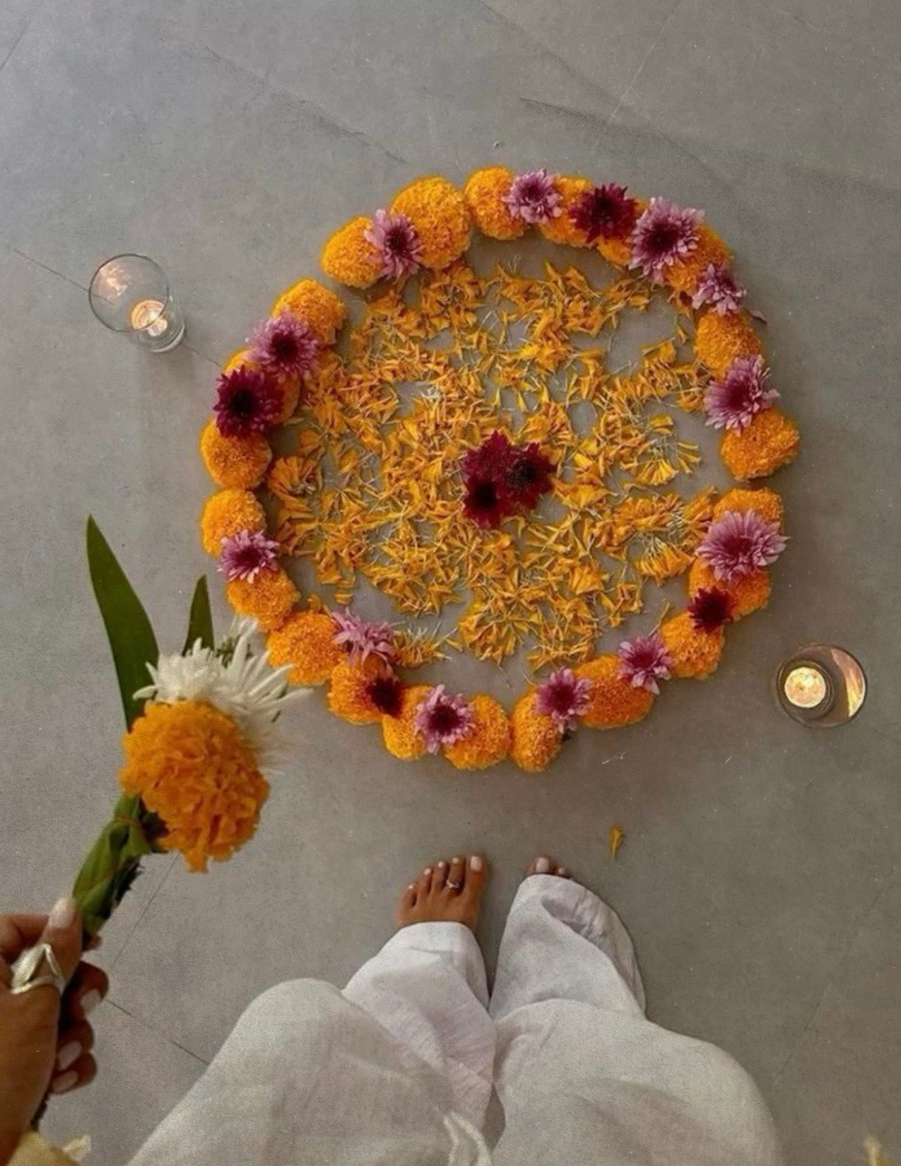 Guest holding a marigold beside a flower intention circle during a private Nuevo Om gathering in Grapevine, Texas.