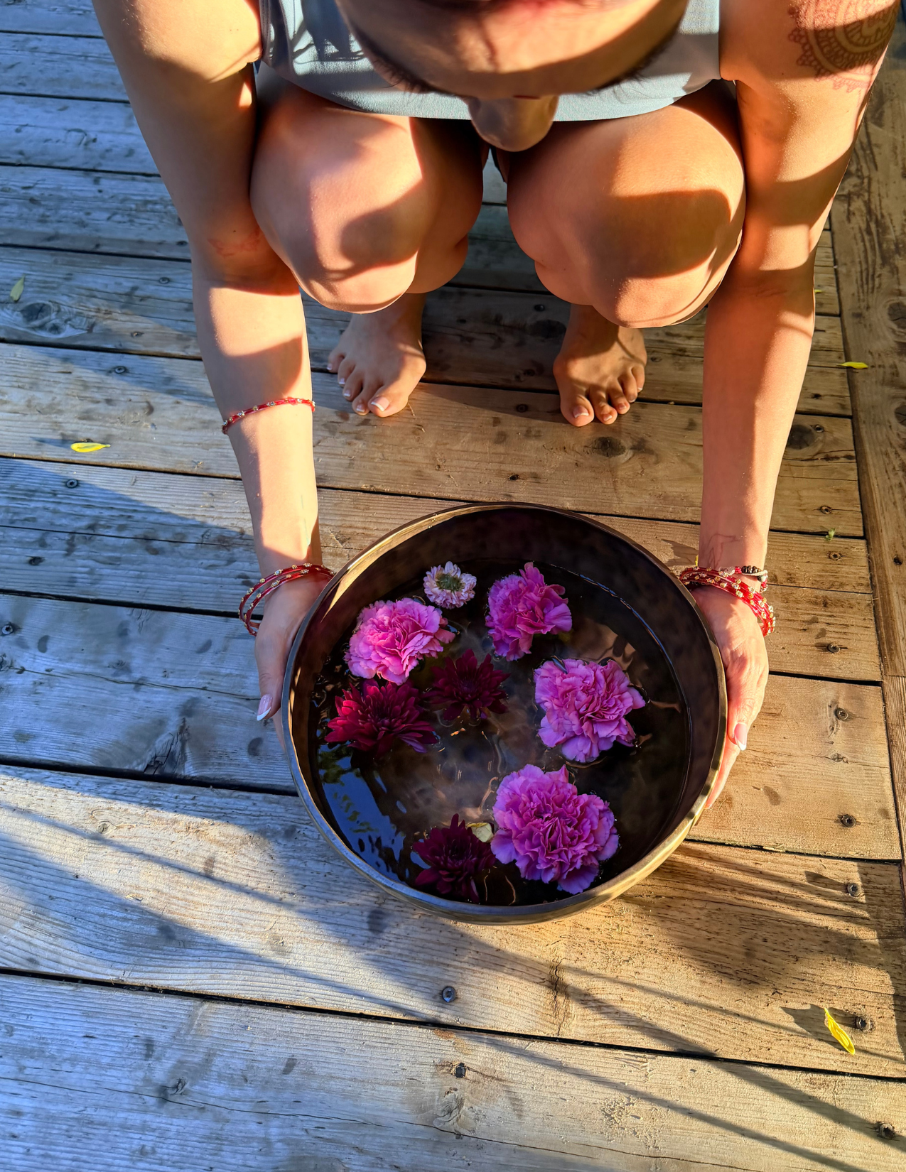 Nuevo Om facilitator holding a bronze bowl filled with floating flowers during a private ritual gathering in Grapevine, Texas.