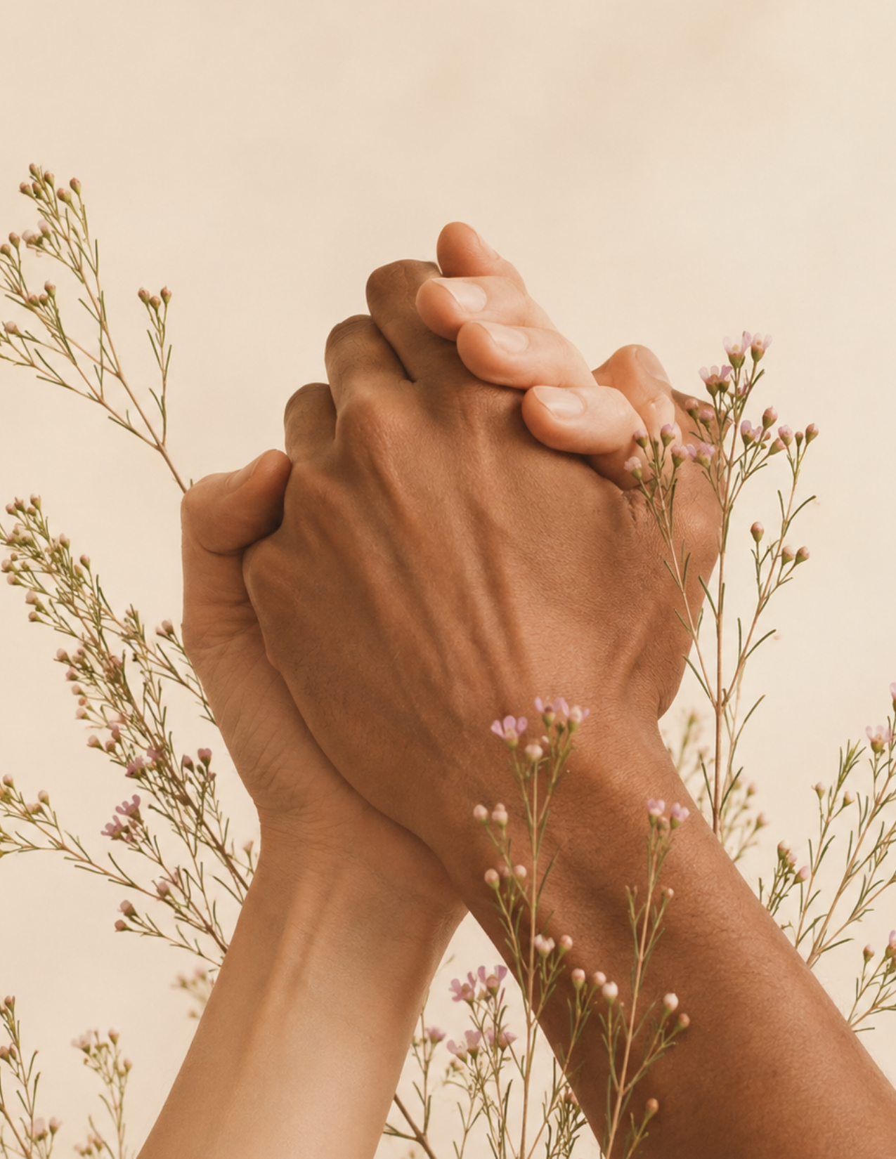 Hands joined together with delicate flowers, representing connection within the Nuevo Om community.