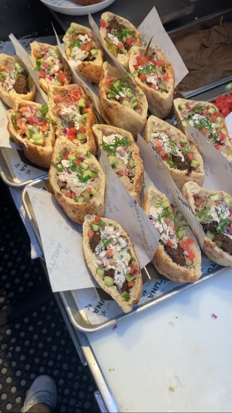 Several chicken shawarma sandwiches filled with meat, tomatoes, cucumbers, onions, and herbs, served on pita bread.