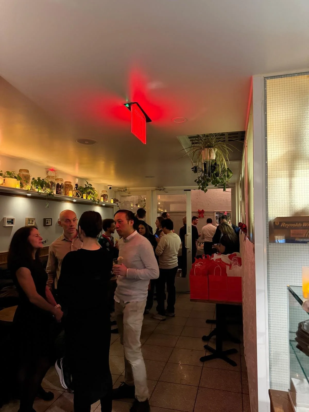 People standing and enjoying the company of others with drinks in the main dining room and the covered patio in a standing cocktail hour party/event at fortuna