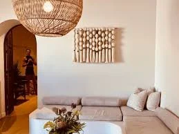 Living room with a beige sectional sofa, decorative wall art, and a large woven pendant light.