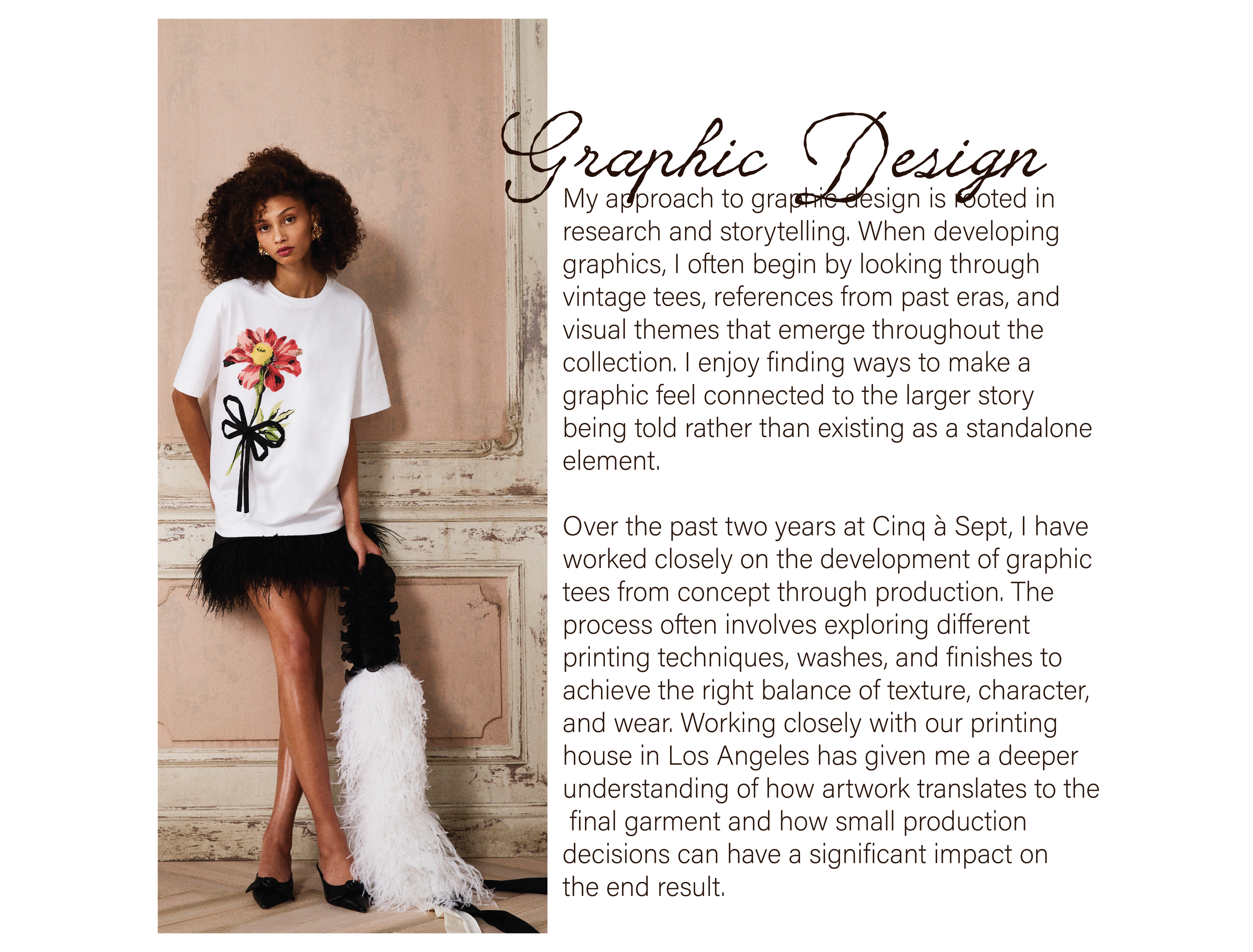 A woman stands against a vintage wall, wearing a white oversized t-shirt with a large floral graphic and black bow design. She has curly hair, gold earrings, and black heels, with one leg slightly bent and a coiled black object near her feet.