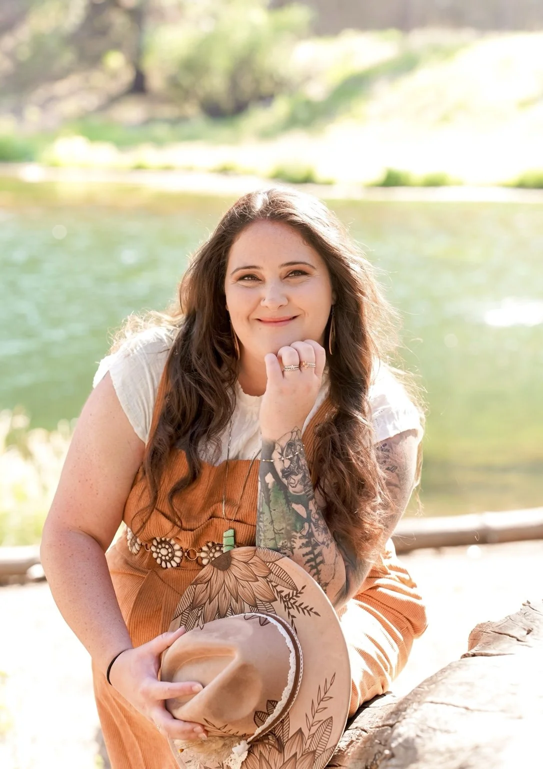 Claire Ramirez-Yocum, therapist at Rooted Pines Healing, seated beside a mountain lake.