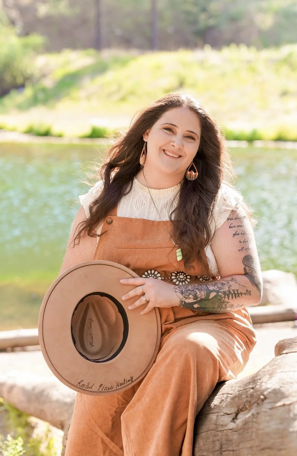 Claire Ramirez-Yocum, therapist at Rooted Pines Healing, smiling beside a mountain lake.