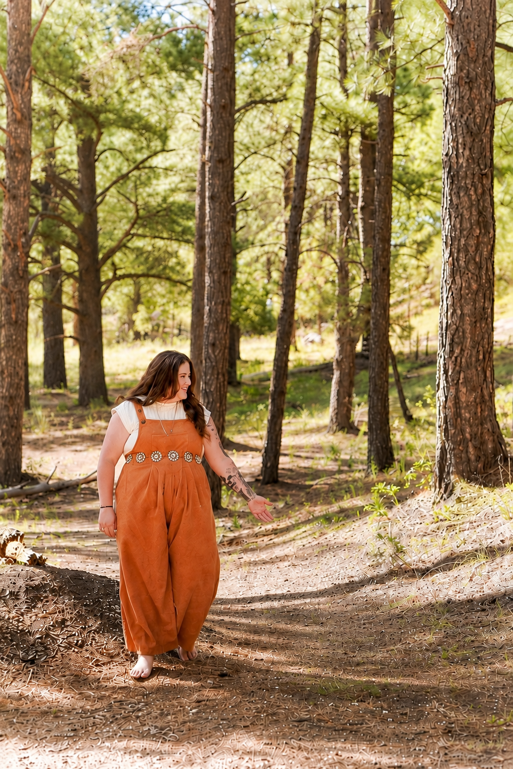 Woman walking barefoot along a sunlit path through a pine forest.