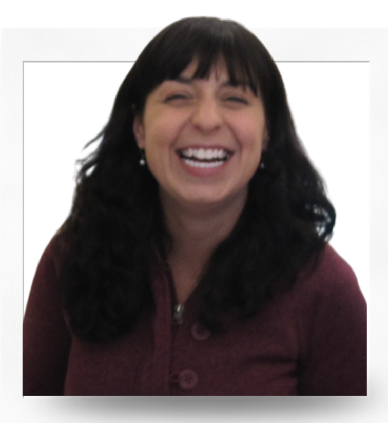 A woman with black hair and bangs, smiling widely, wearing pearl earrings and a maroon zip-up jacket.