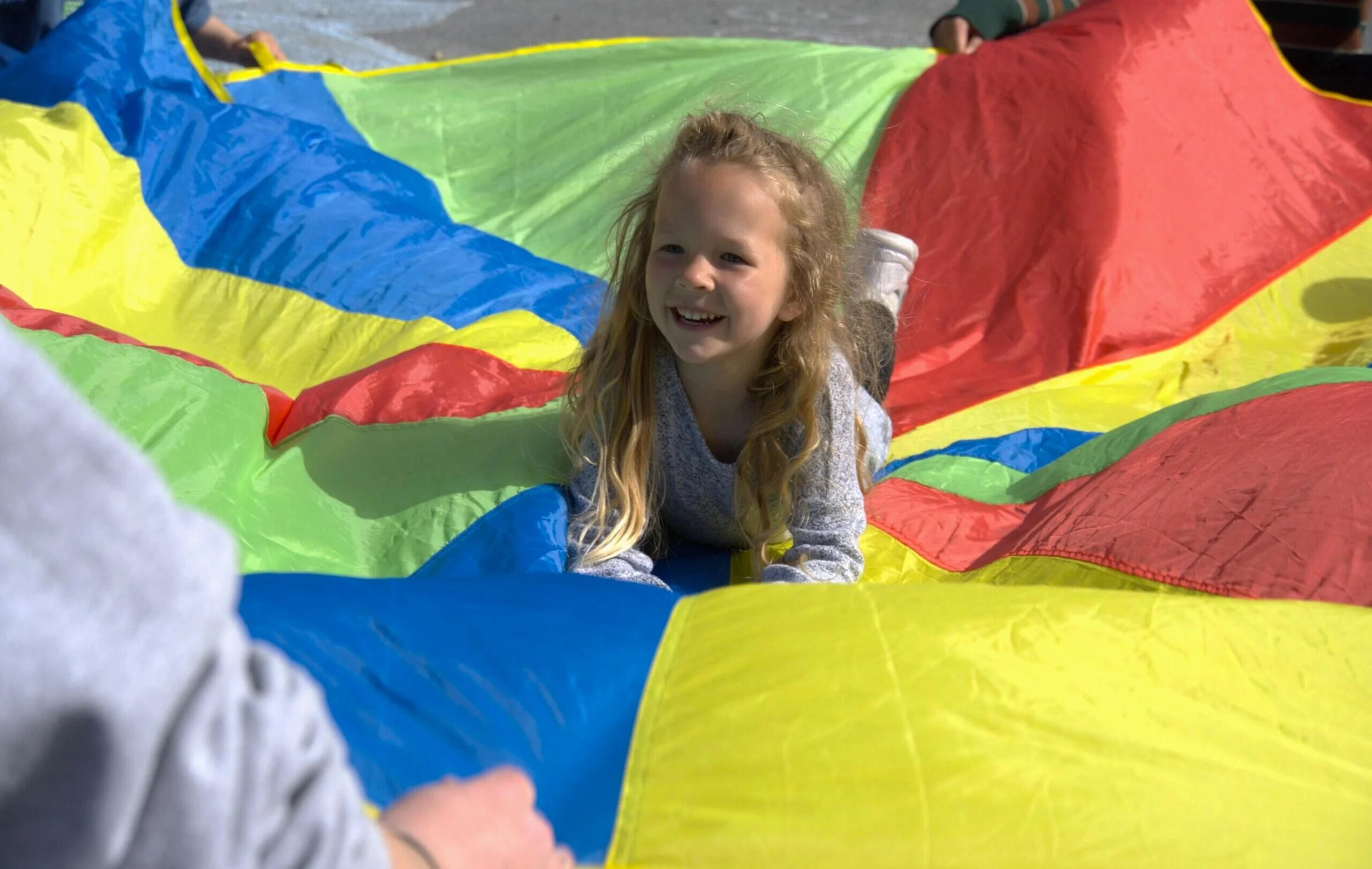 Child at play in a rainbow parachute in Sitka.