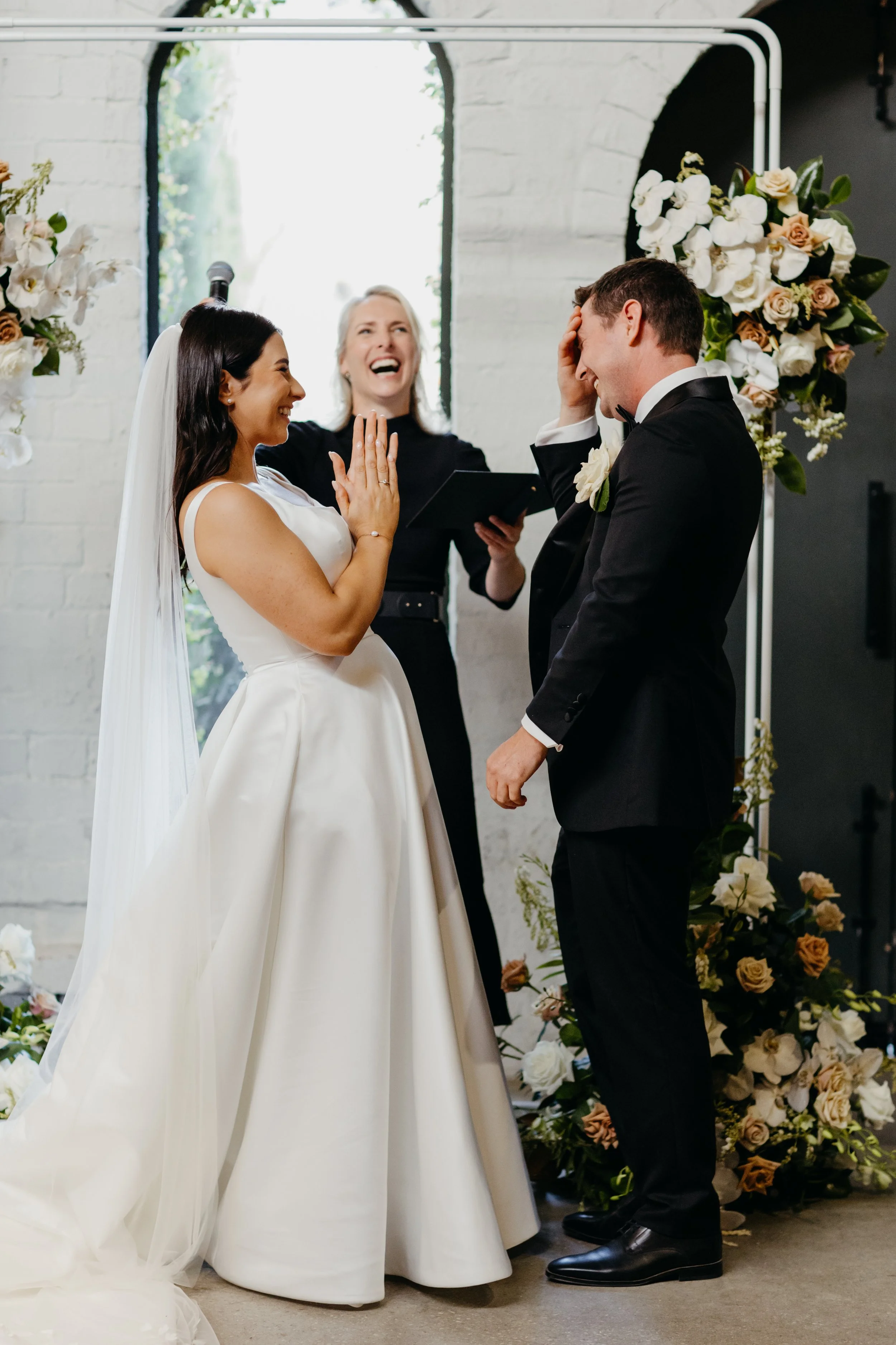 Joyful wedding ceremony moment as couple laugh together during a personalised ceremony led by their celebrant.