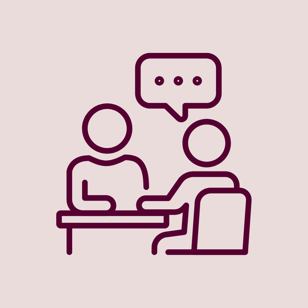 Two people sitting at a table having a discussion, one with a speech bubble above.