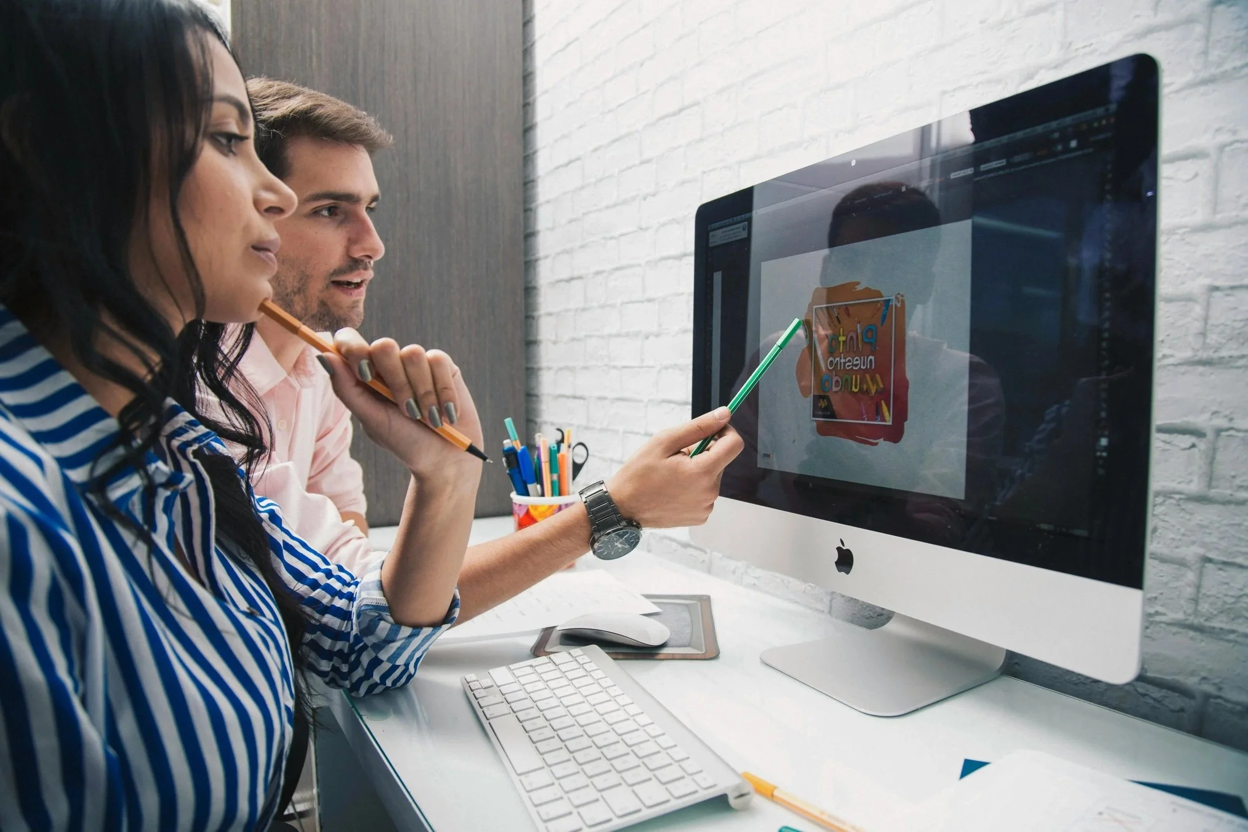 Design team reviewing artwork and print layout concepts on a desktop computer