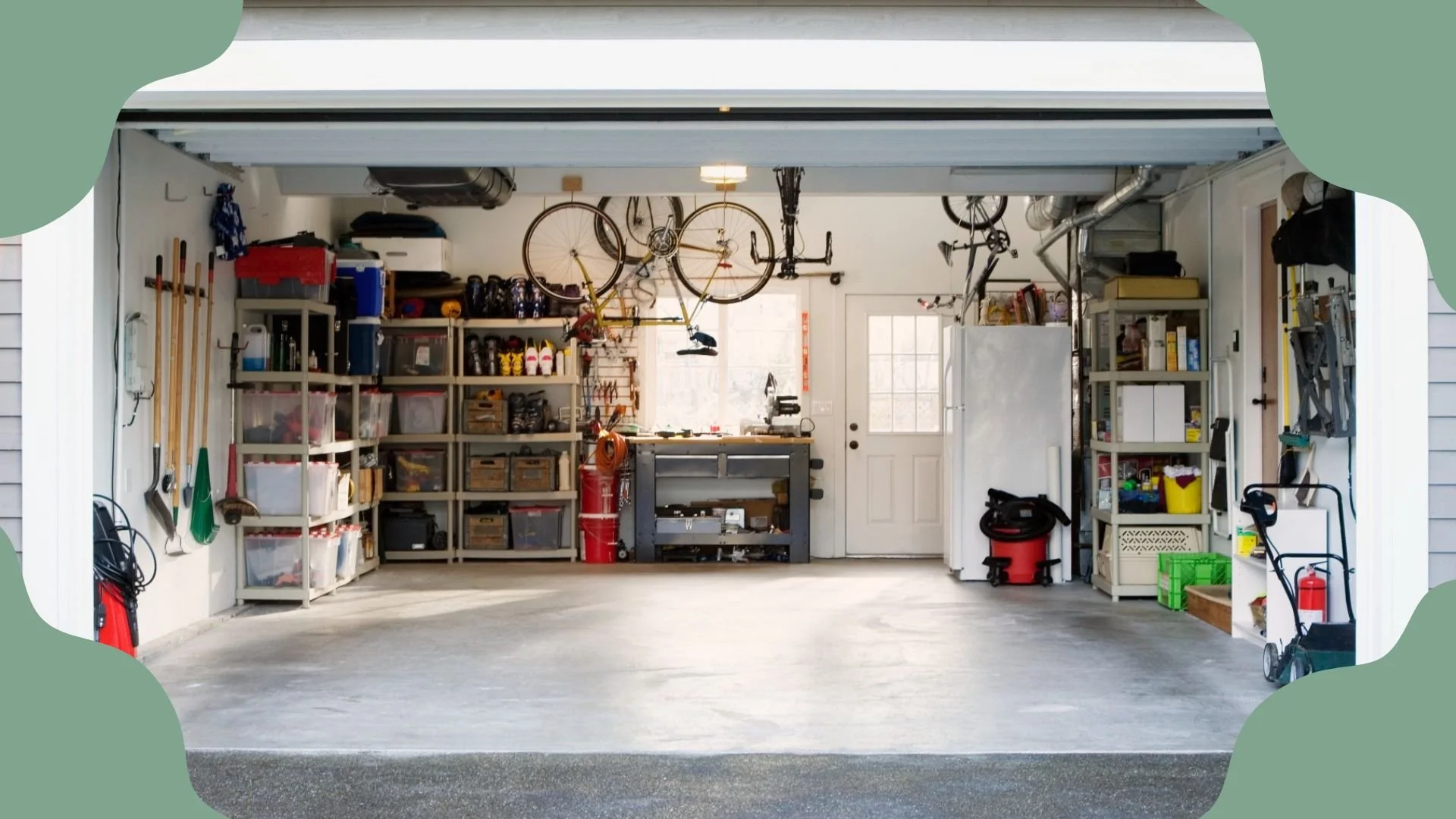The image shows a tidy garage with organized shelves holding tools, storage bins, and supplies. Several bicycles are hanging from the ceiling, and there is a workbench near the back door. Various garage items are neatly stored along the sides.