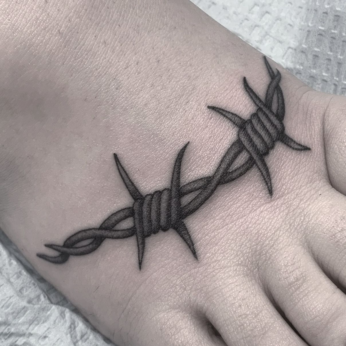 Fineline Blkackwork barbed wire tattoo on a foot