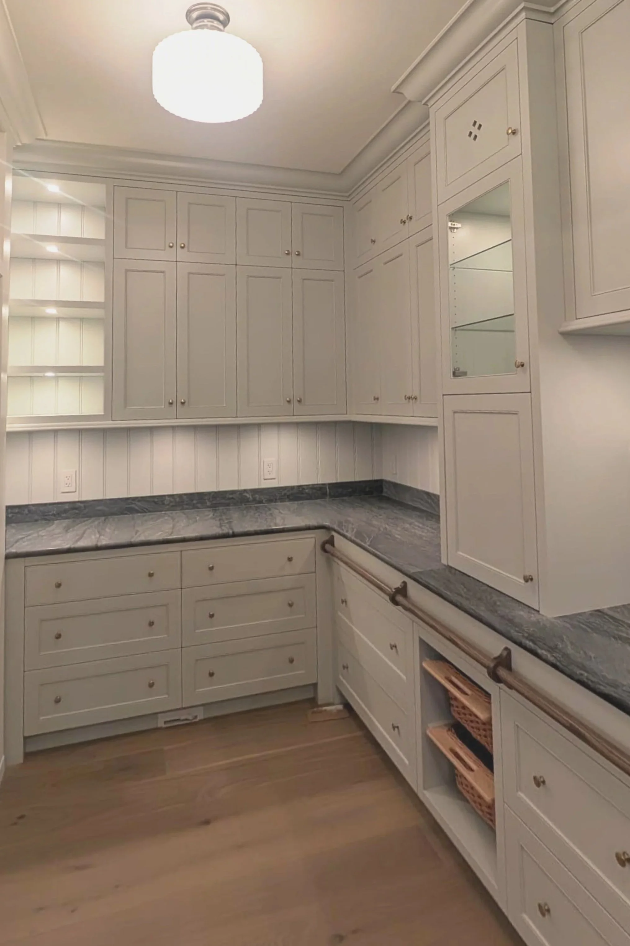 Kitchen with white cabinets, dark granite countertops, wooden floor, and a ceiling light fixture.
