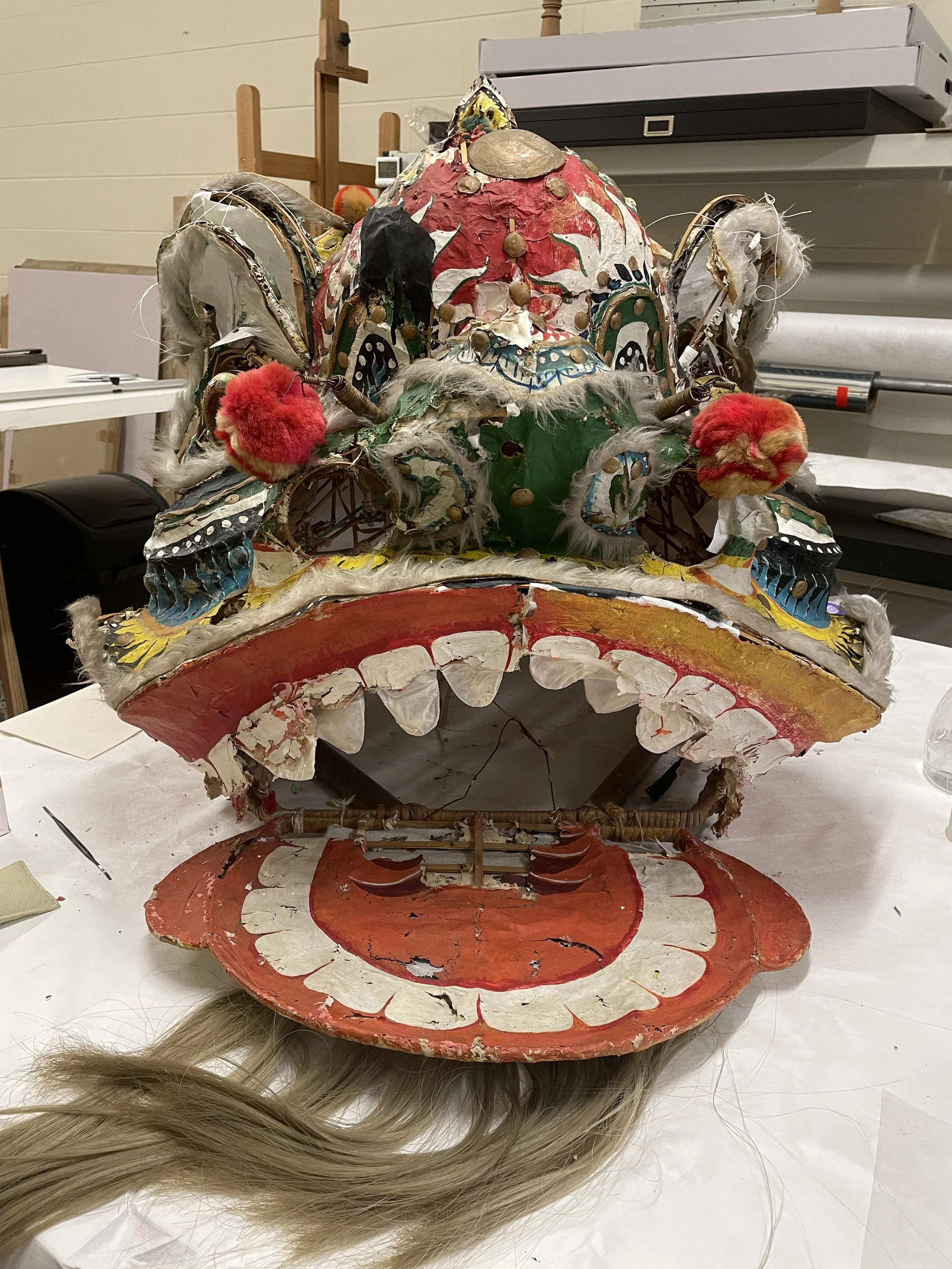 A decorated dragon mask or costume with intricate and colorful decorations, feathers and other elements.