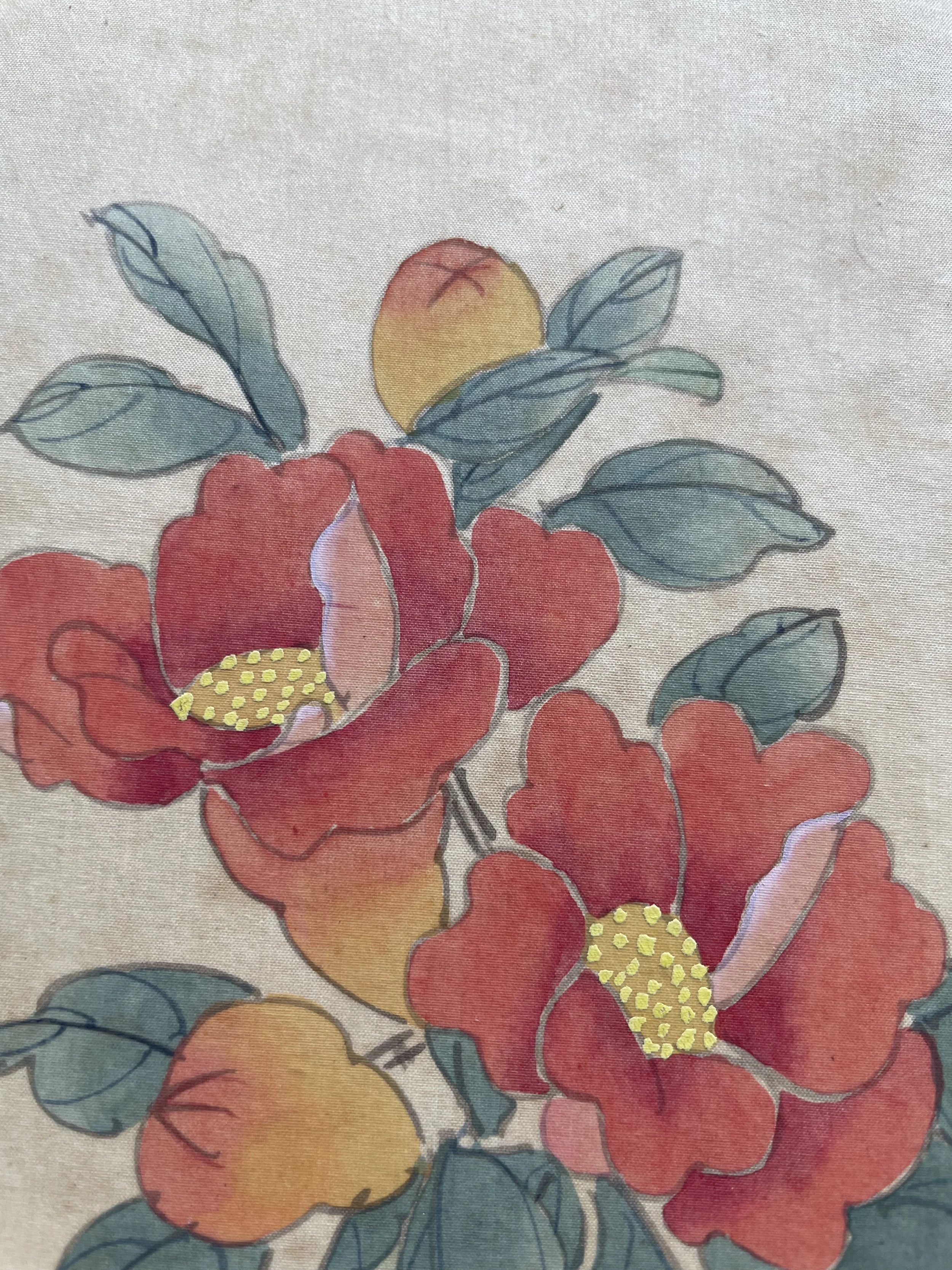 Close-up of a fabric with a colorful floral pattern featuring red and orange flowers with yellow centers, green leaves, and a single yellow flower with red accents on a light background.