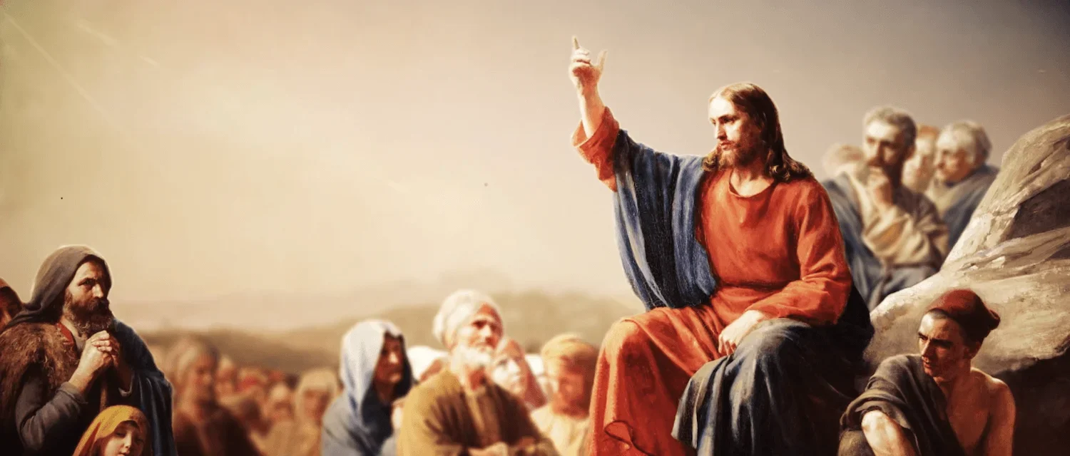 A painting of Jesus Christ explaining something to a crowd, seated on a rock, with followers listening.