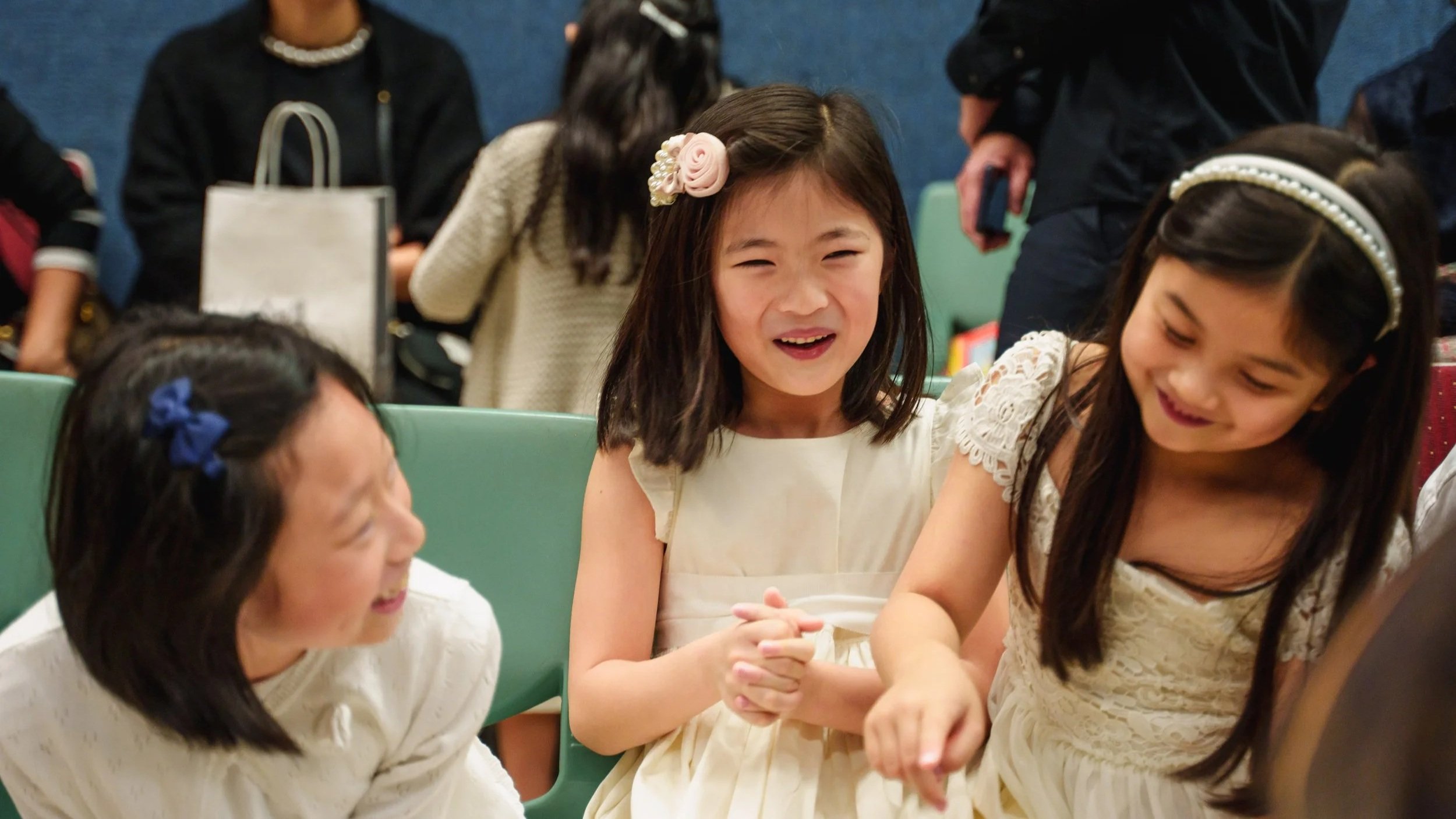 Group of young girls sitting in a circle at a table, laughing and chatting together.