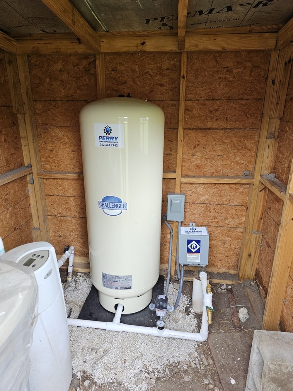 Water heater and plumbing system inside a wooden framed storage room or basement area.