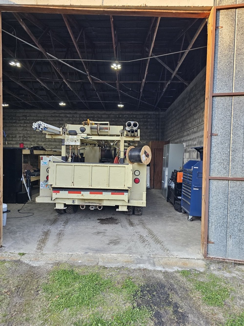 A utility truck parked inside a garage with tools and equipment on the right side.