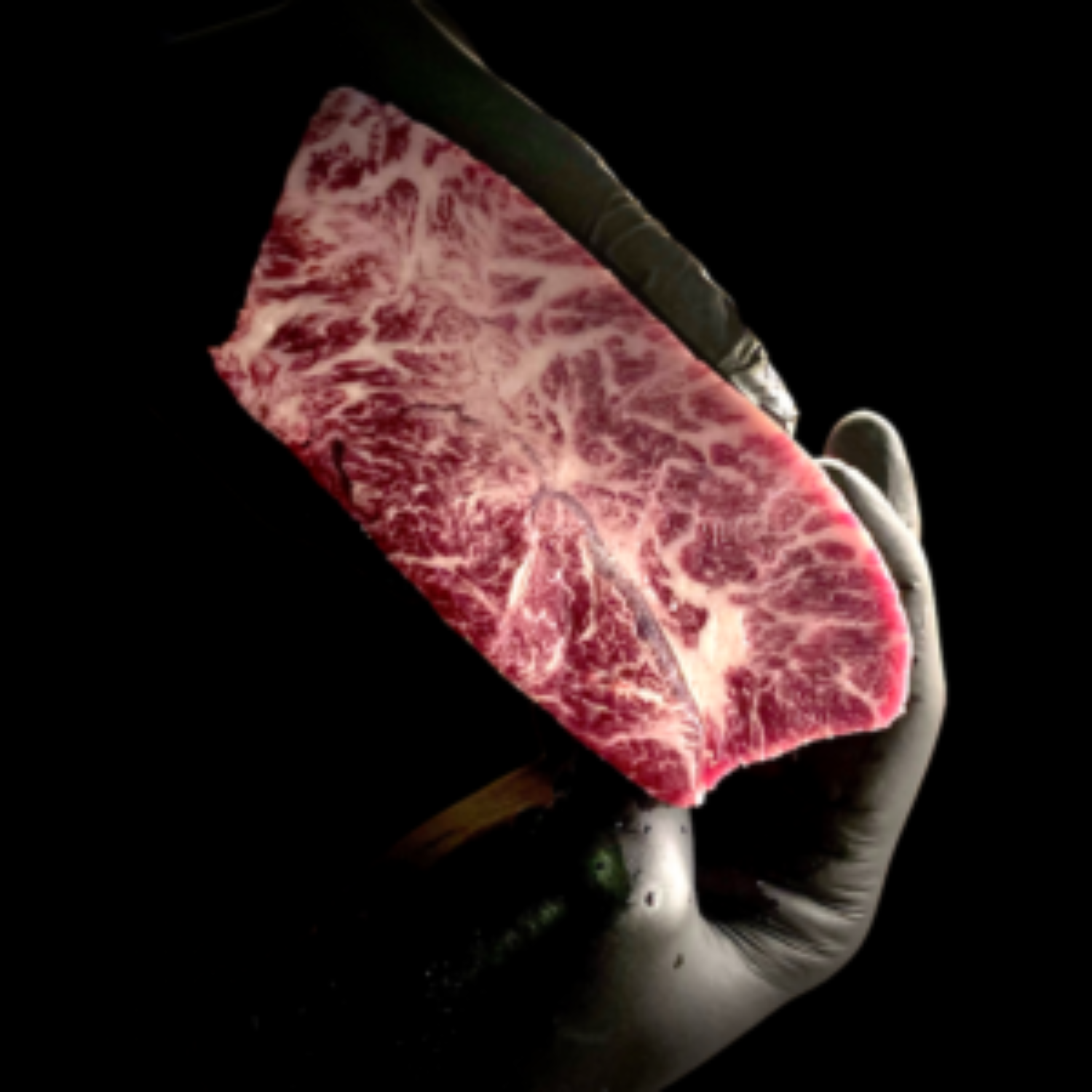 Hand holding a tray with a slice of marbled raw beef, black background