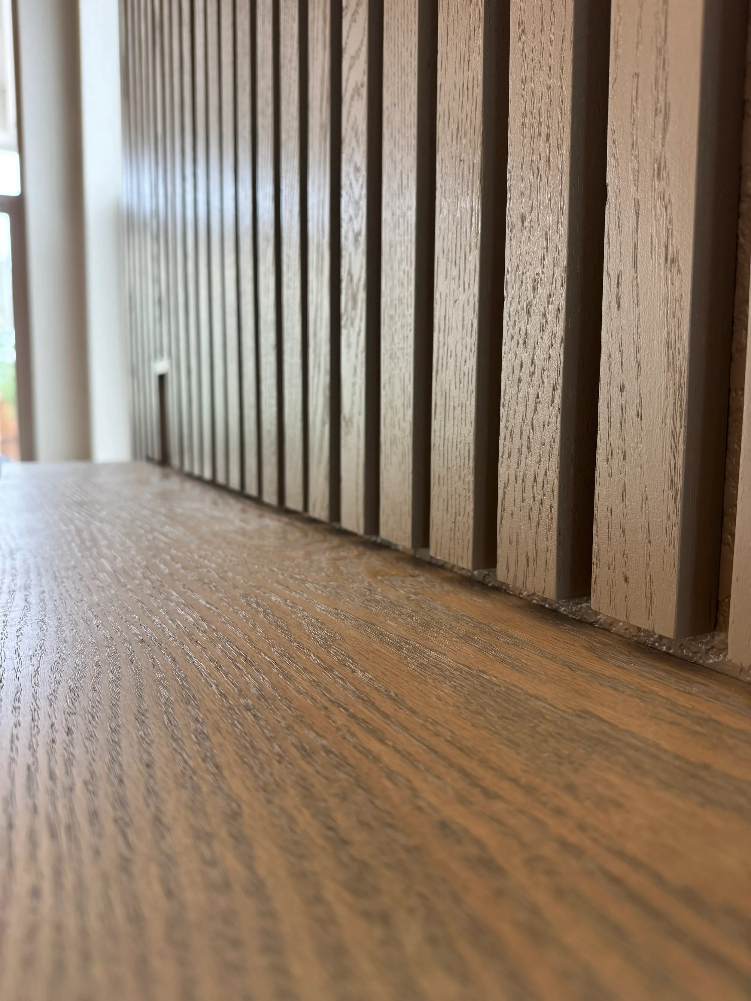 Natural red oak wood slat accent wall with a custom floating shelf in a Denver home