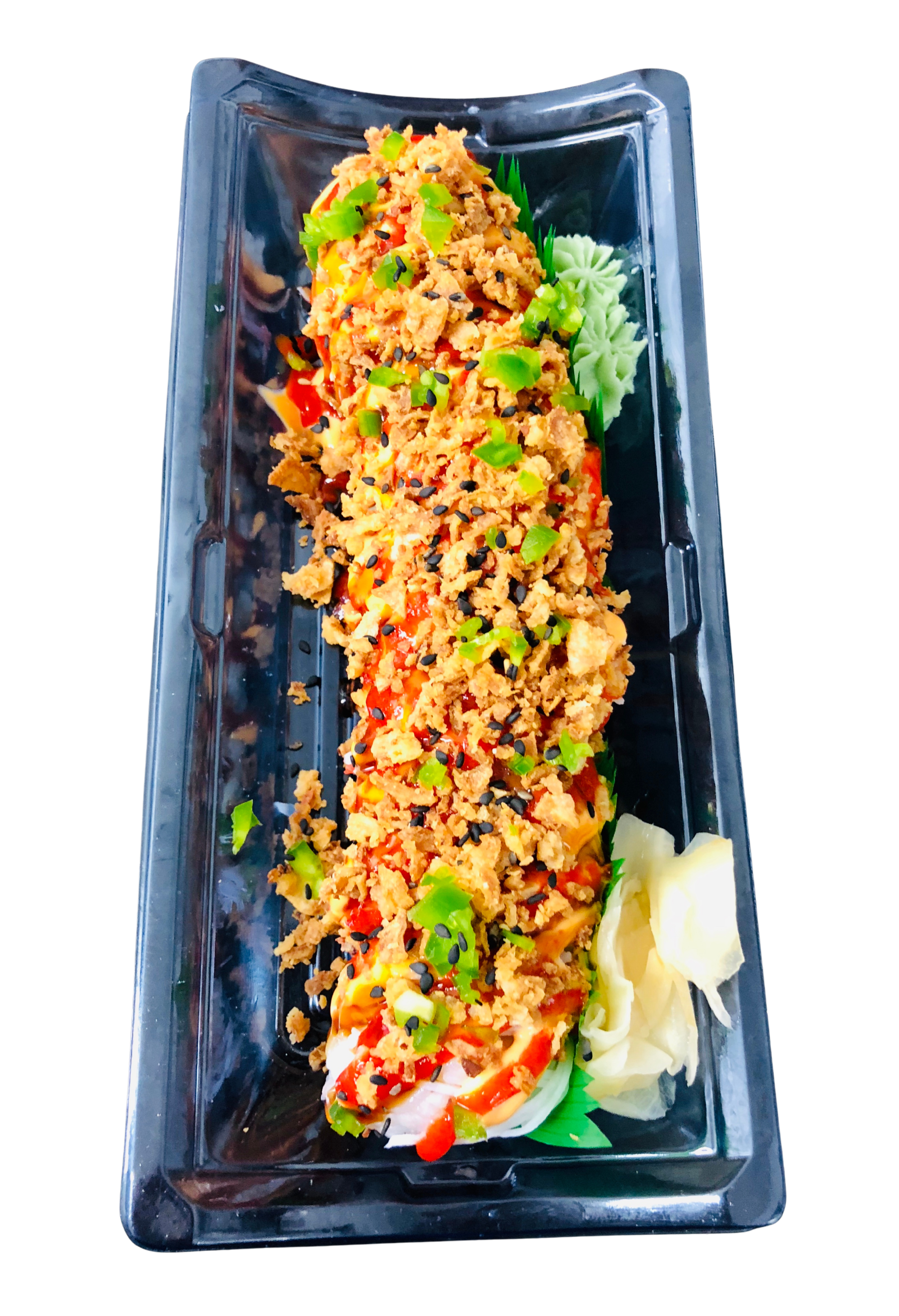 A close-up of a sushi roll in a clear black plastic container, topped with crunchy tempura flakes, chopped green onions, and black sesame seeds, served with a side of pickled ginger.
