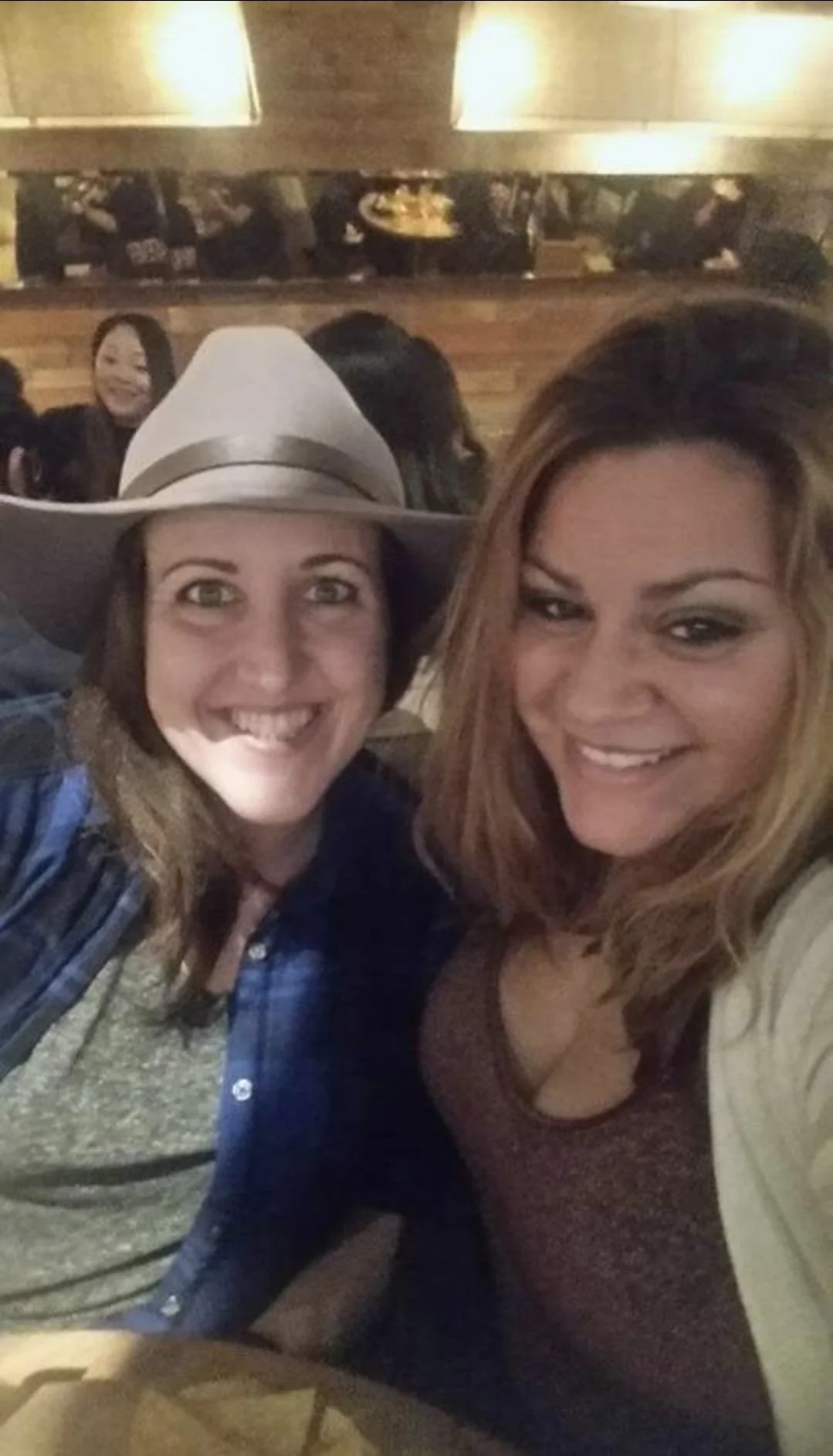 Two women taking a selfie at a restaurant, smiling and enjoying themselves.