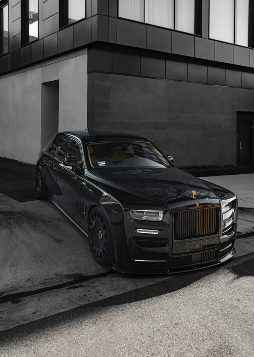 A black luxury sedan parked on the street in front of a modern building with dark gray and black panels.