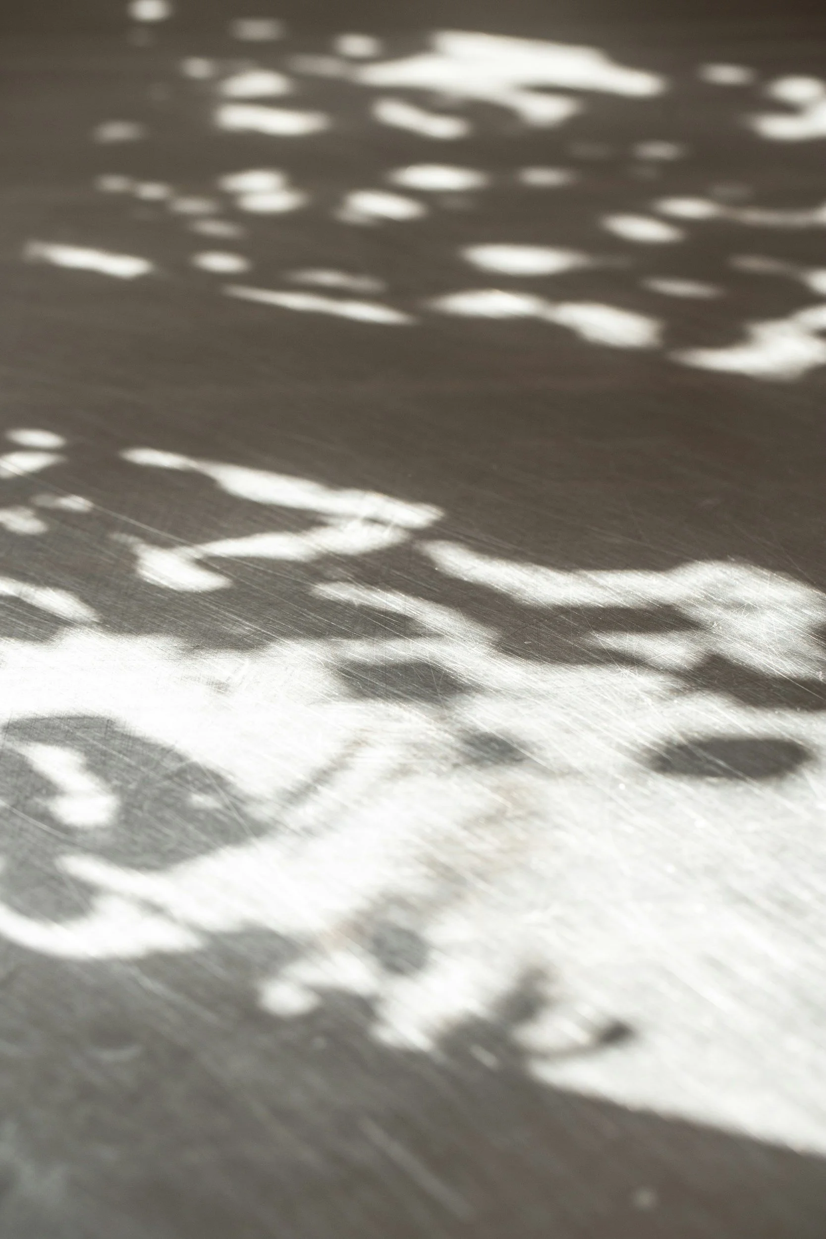 Sunlight casting patterned shadows through a window onto a smooth surface.