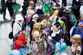 A crowd of people in costumes, including some with colorful wigs and fantasy outfits, gathered at an event or convention.