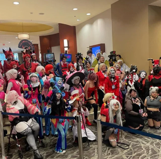 Group of people dressed in colorful cosplay costumes at an indoor event.