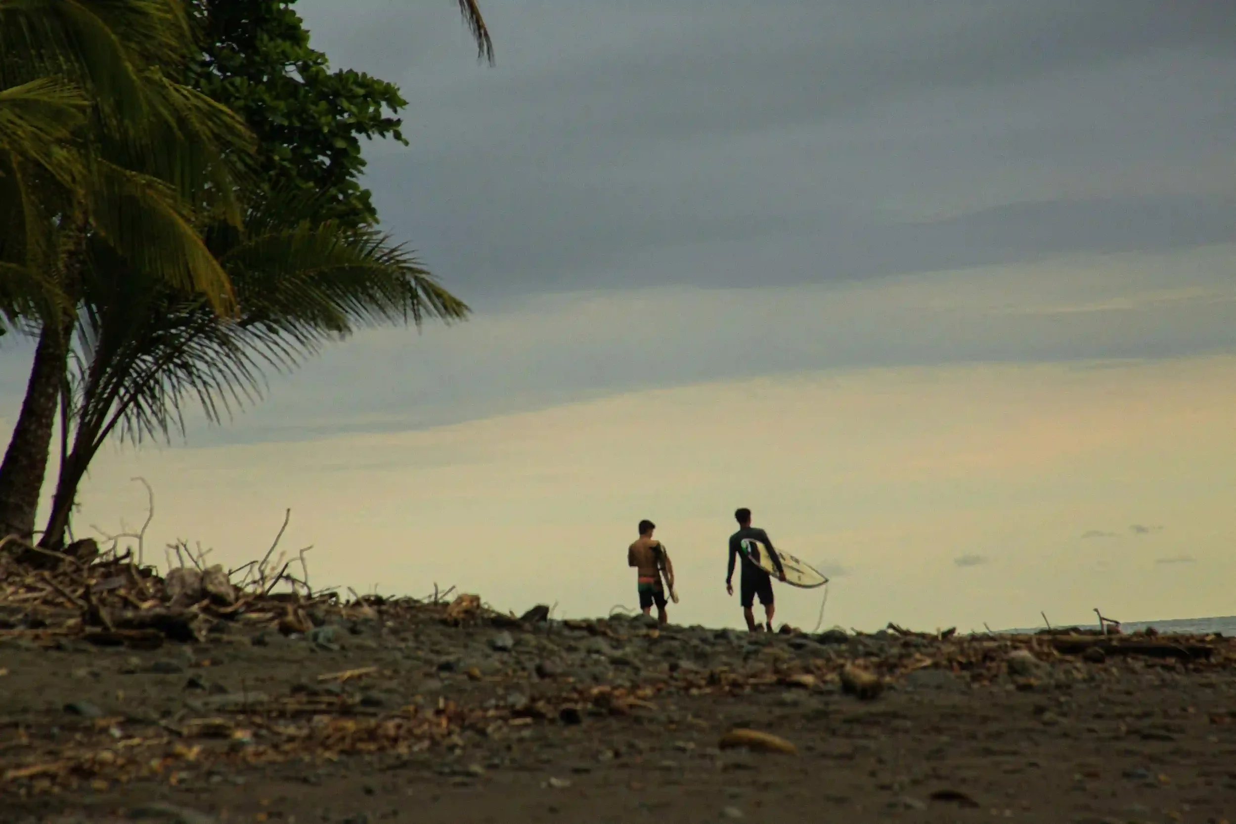 Two Latin American surfers walking on a beach in Costa Rica