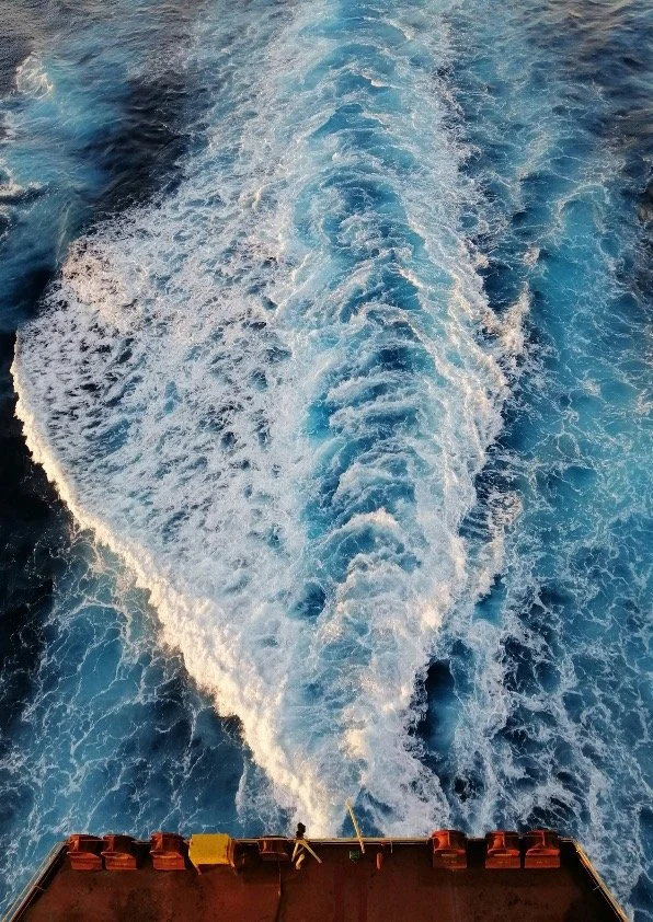 船の後部から見た、海に広がる白波と青い海の水しぶきの写真