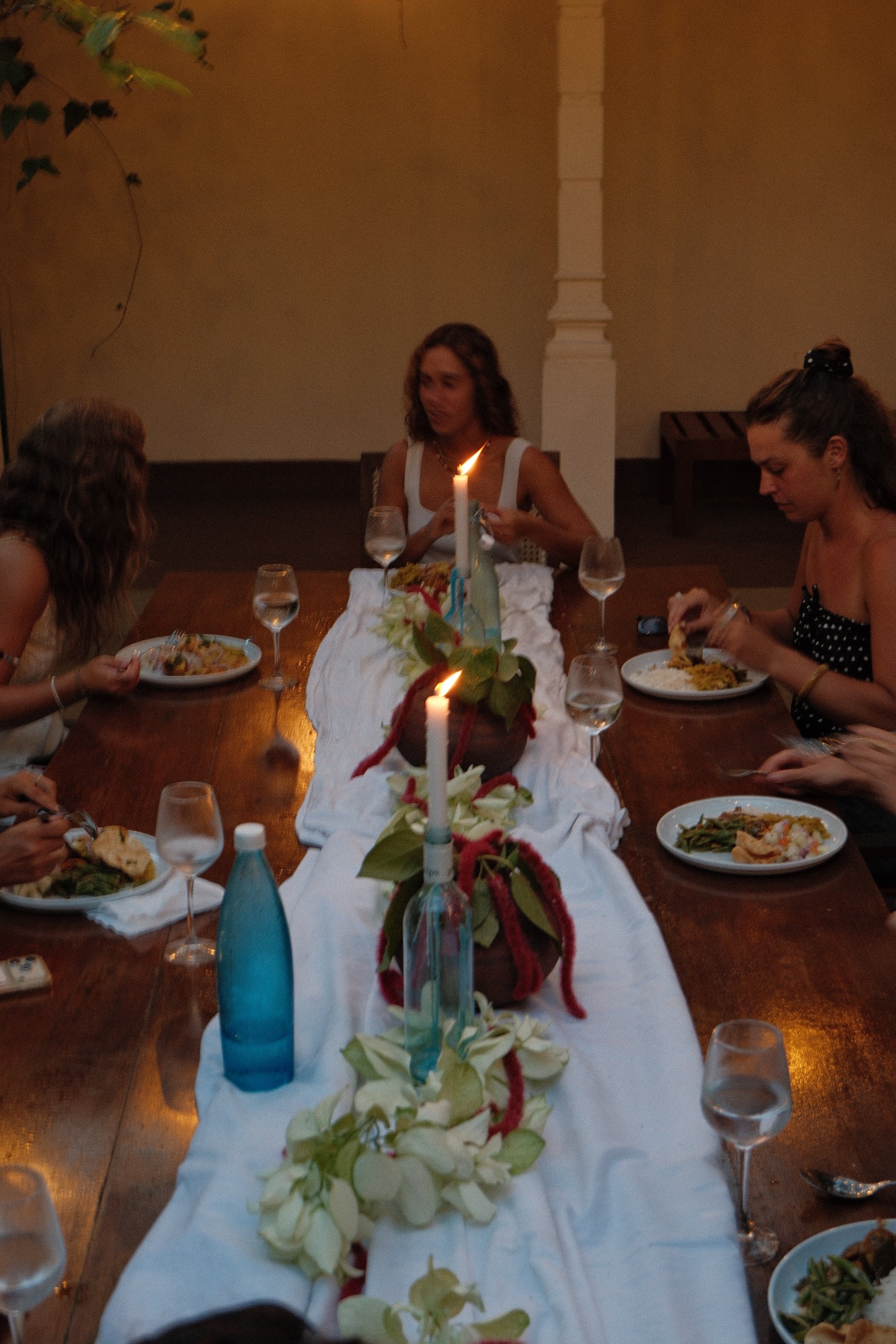 A group of women sitting around a dining table with a floral centerpiece.