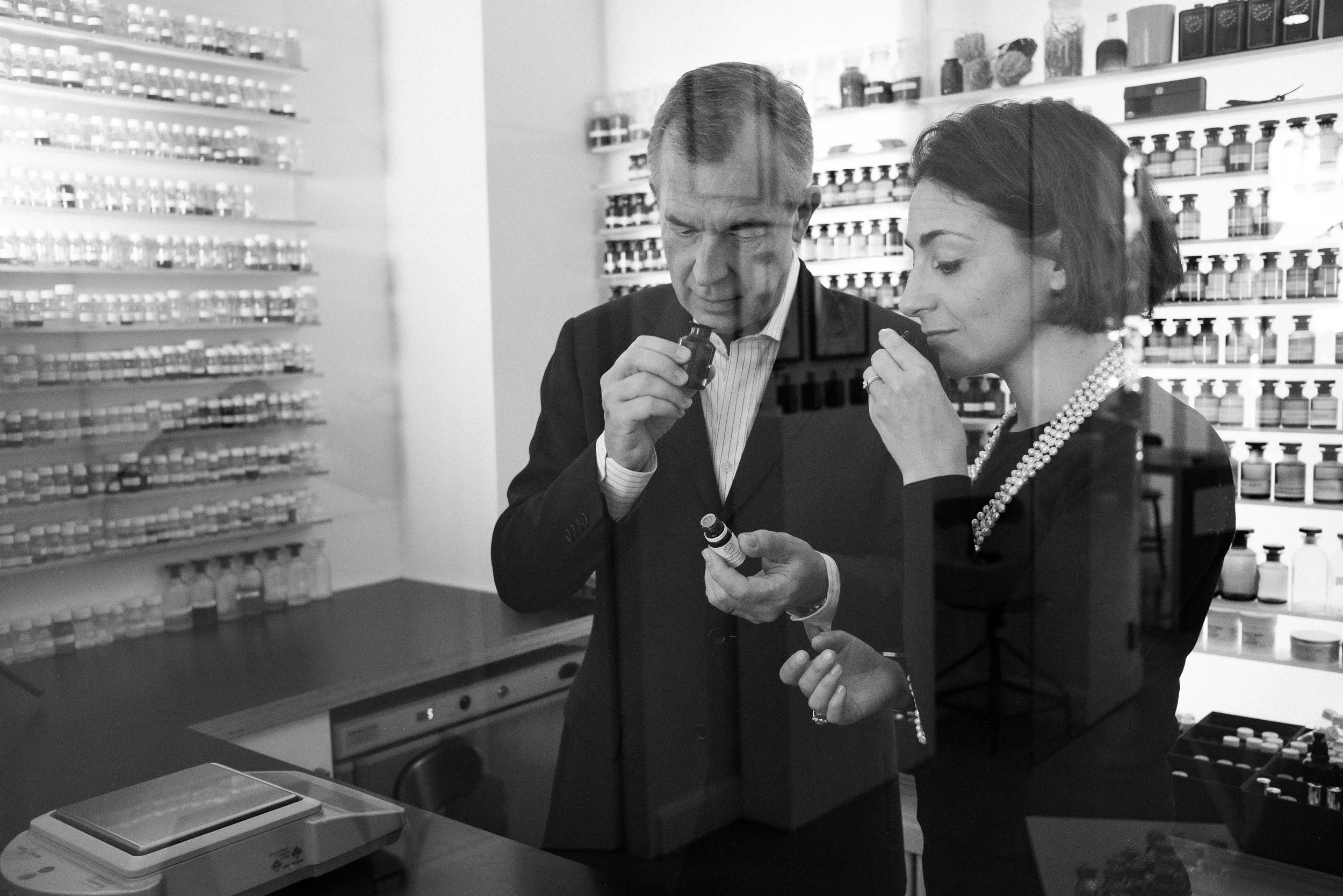 Two women and a man looking at medication bottles in a pharmacy, with shelves of bottles around them.