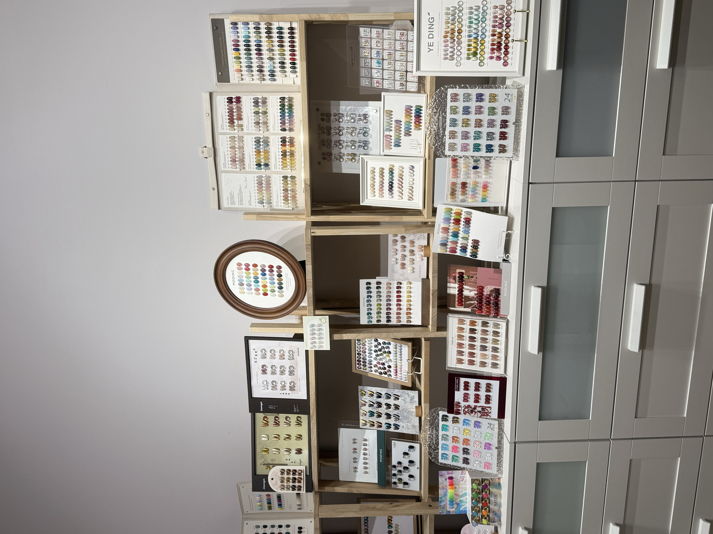 Display of various nail gel polish colors and designs arranged on white shelves and boards in Getsumei beauty.