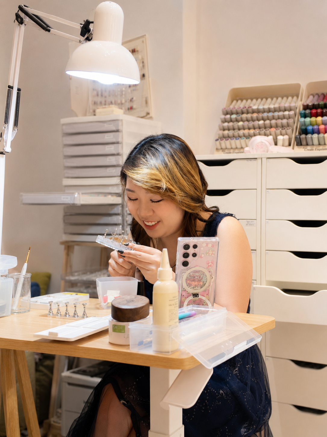 Jx working on nail art at a beauty station with various nail gel polish colors and tools around her in Getsumei Beauty.