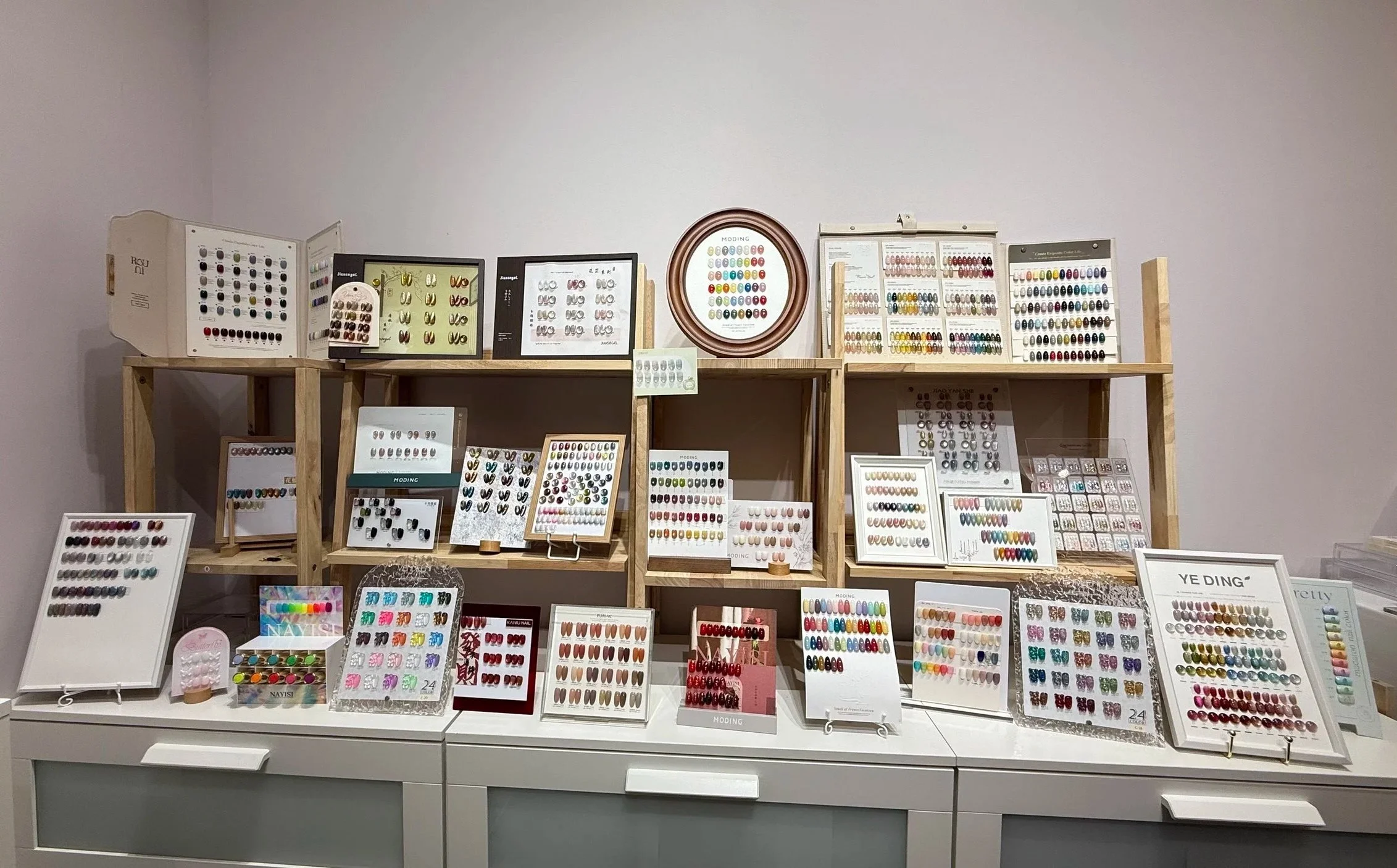 Display of various gel nail polish color samples in Getsumei Beauty arranged on shelves and boards.