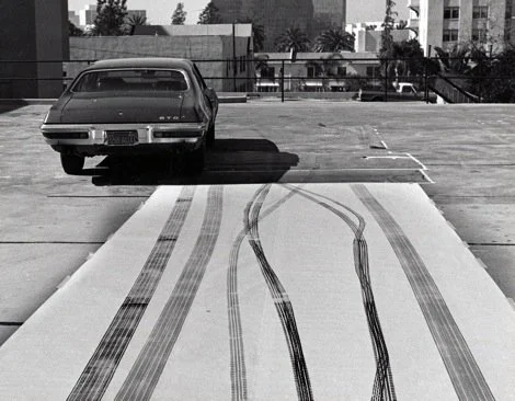 A remote-controlled car has made tire marks on a parking lot rooftop.