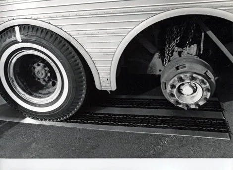 Close-up of a vehicle's rear wheel with the tire removed, exposing the brake drum and chain.